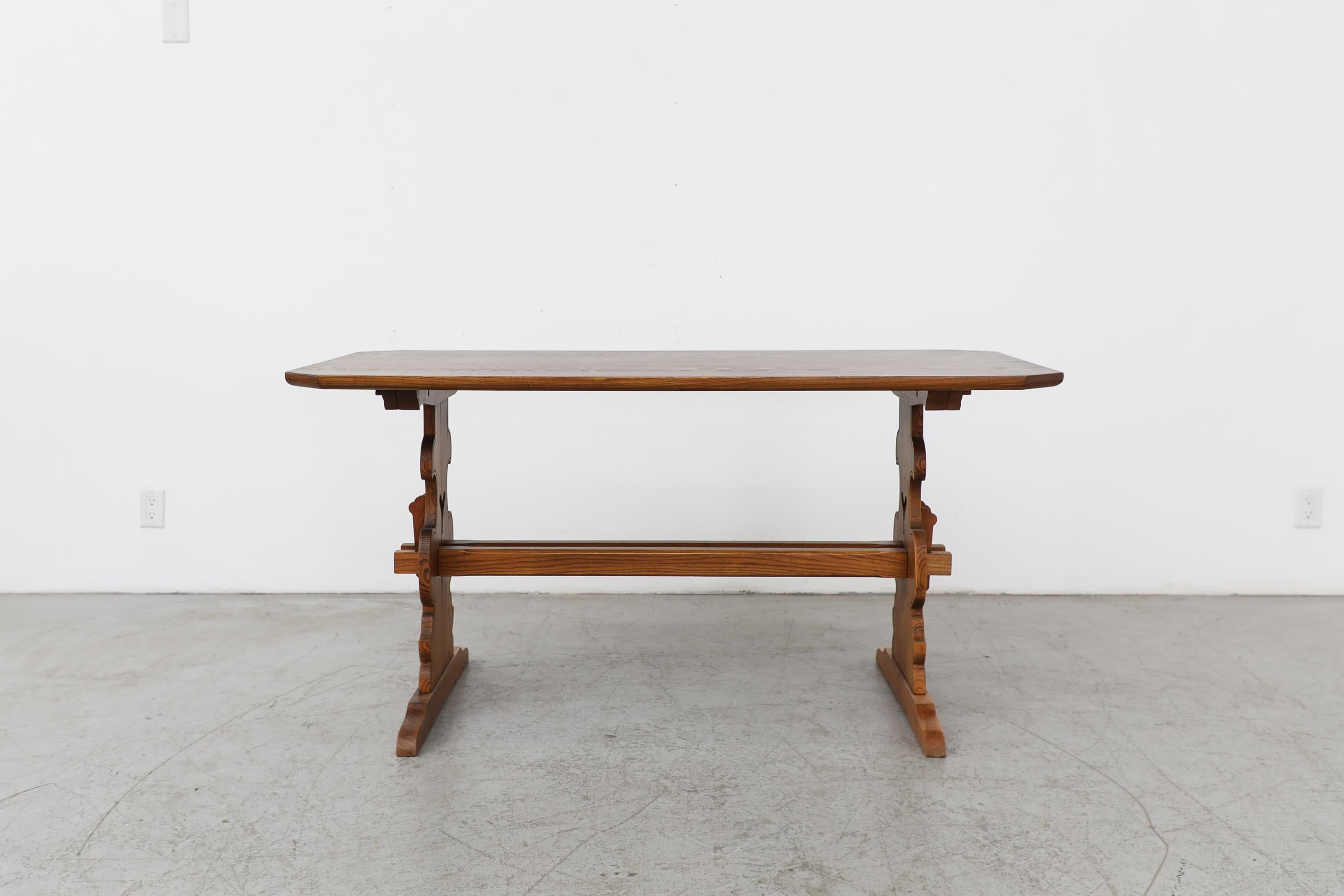 Ornante Tyrolean style dining table with carved trestle base and clipped corners. A versatile and attractive dark toned natural wood table perfect for a cozy nook or an entry way. In original condition with moderate wear and scratching consistent