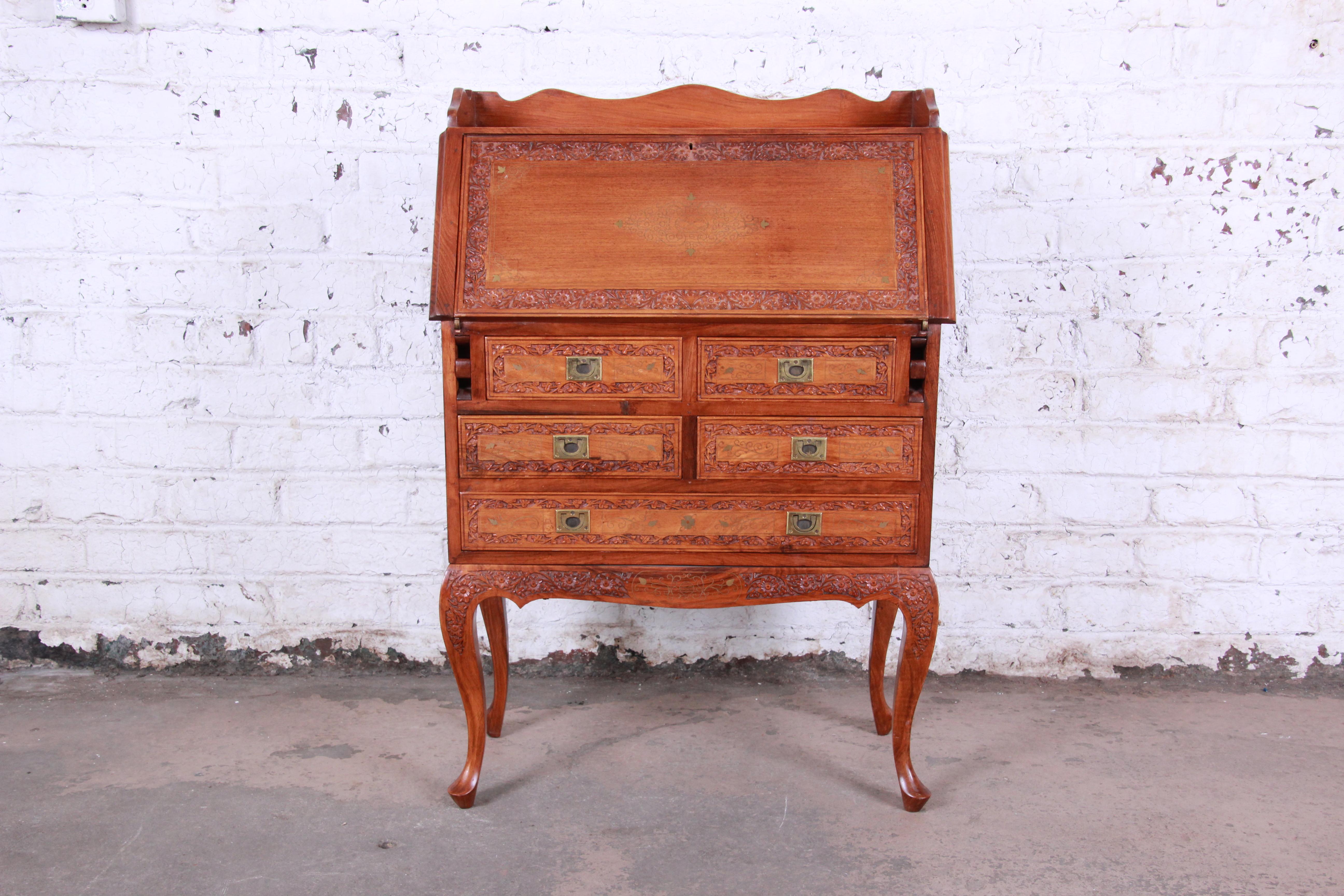 A gorgeous ornate carved elm wood Chinoiserie secretary desk. The desk features beautiful carved wood and inlaid brass details. The campaign style hardware is original, and it has nice Queen Anne style legs. The desk is petite but still offers good