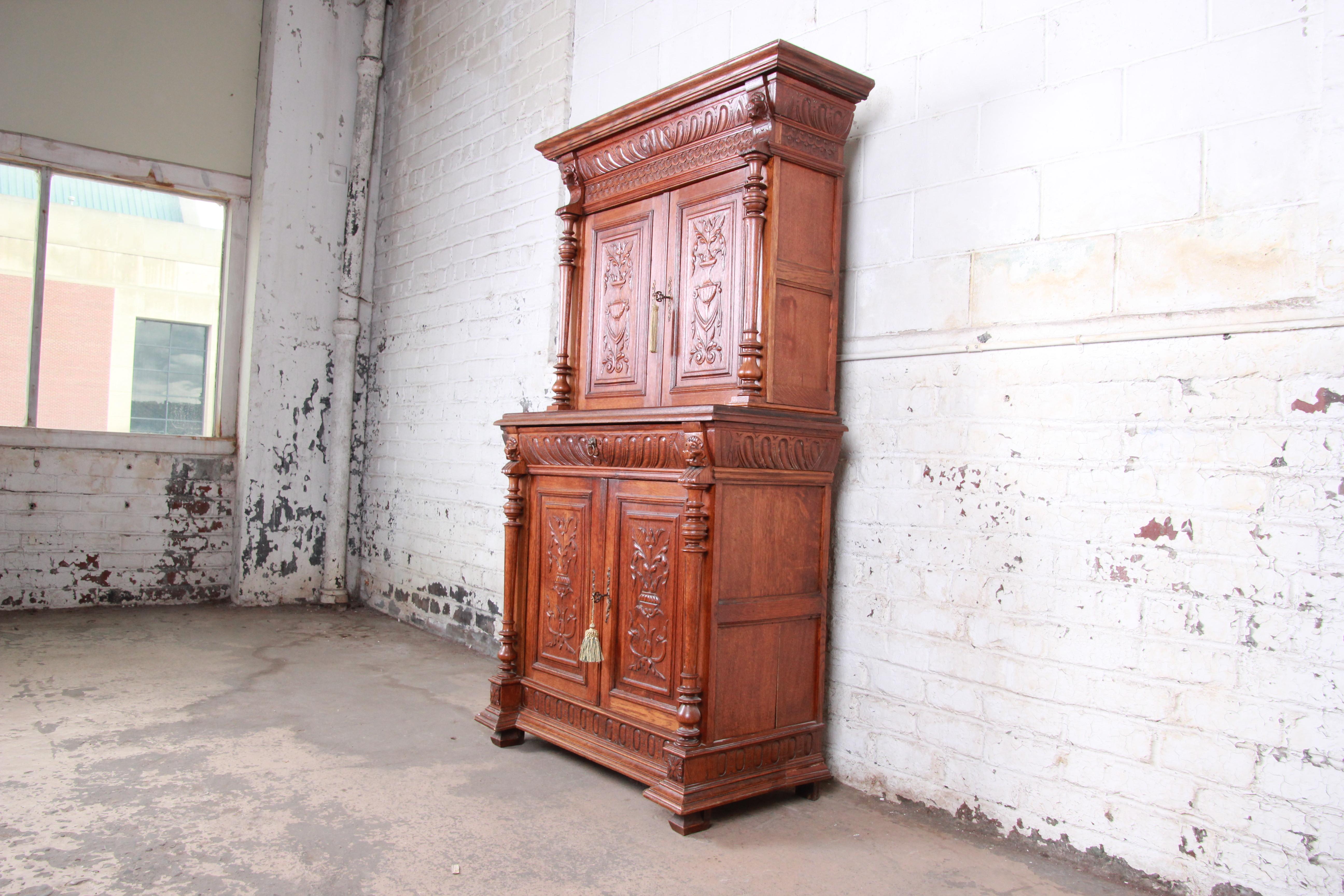 An exceptional ornate carved oak sideboard hutch or bar cabinet made in France, circa 1900. The cabinet features solid oak construction with heavy carvings including lion heads, urns, and floral and figural patterns. It offers excellent storage,