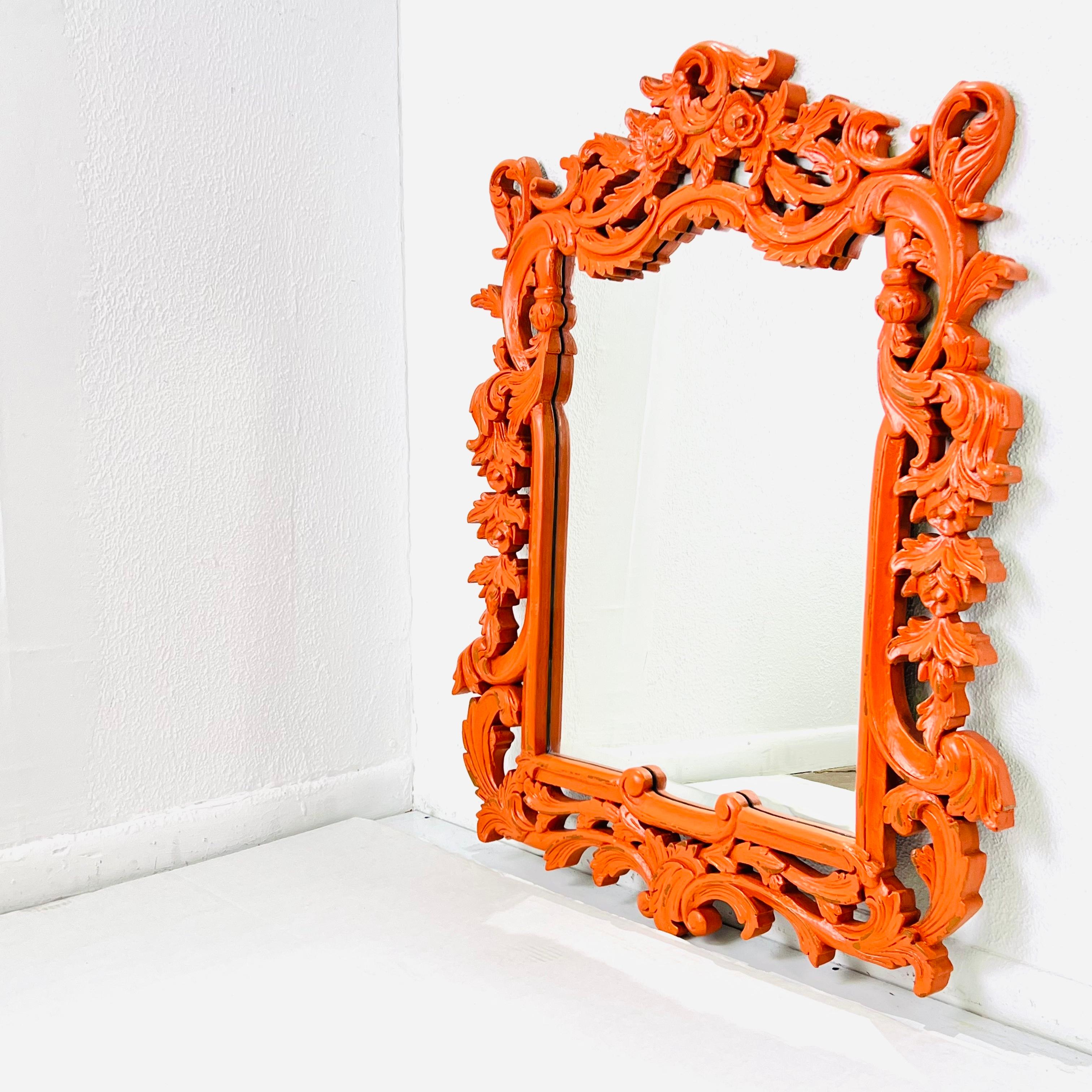 Large hand carved wood wall mirror. Flower and leaf detail on frame, reinvented with orange lacquer. Both mirror and frame in good vintage condition.