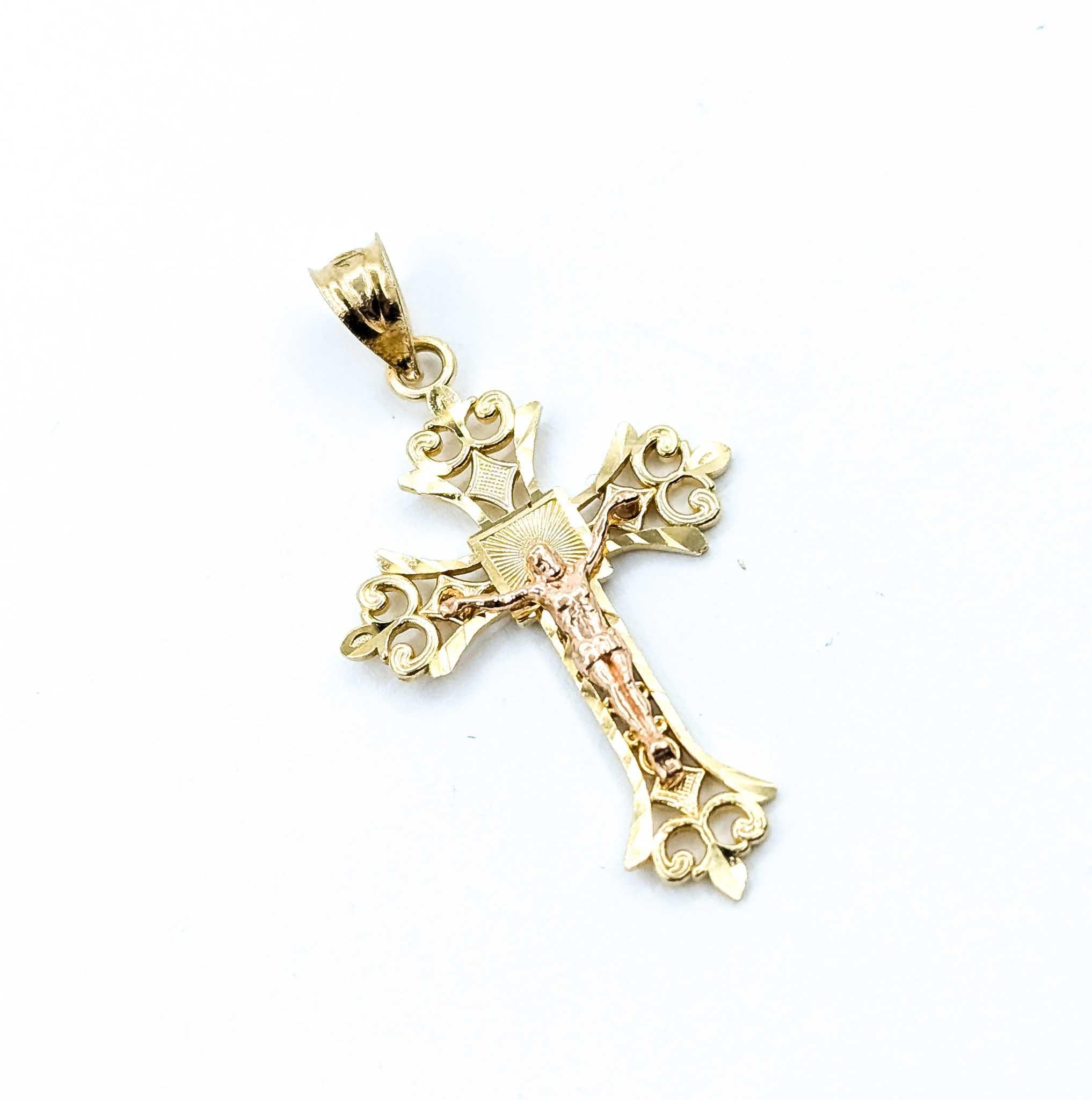 Ce pendentif crucifix magnifiquement détaillé est réalisé en or jaune 14k. Il mesure 1,5 pouce de long sur 0,75 pouce de large et pèse 1,89 gramme. Le design orné présente des fioritures et des gravures complexes, encadrant la figure finement rendue