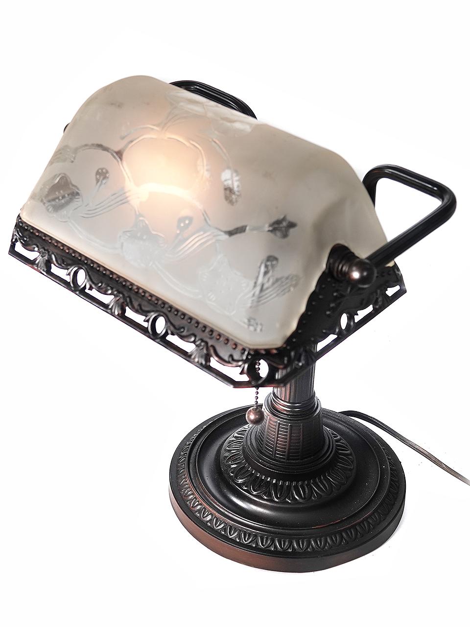 This banker's desk lamp or piano lamp has an original floral design glass shade that is cut to clear on a frosted background. The decorative metal work is finished in black.  