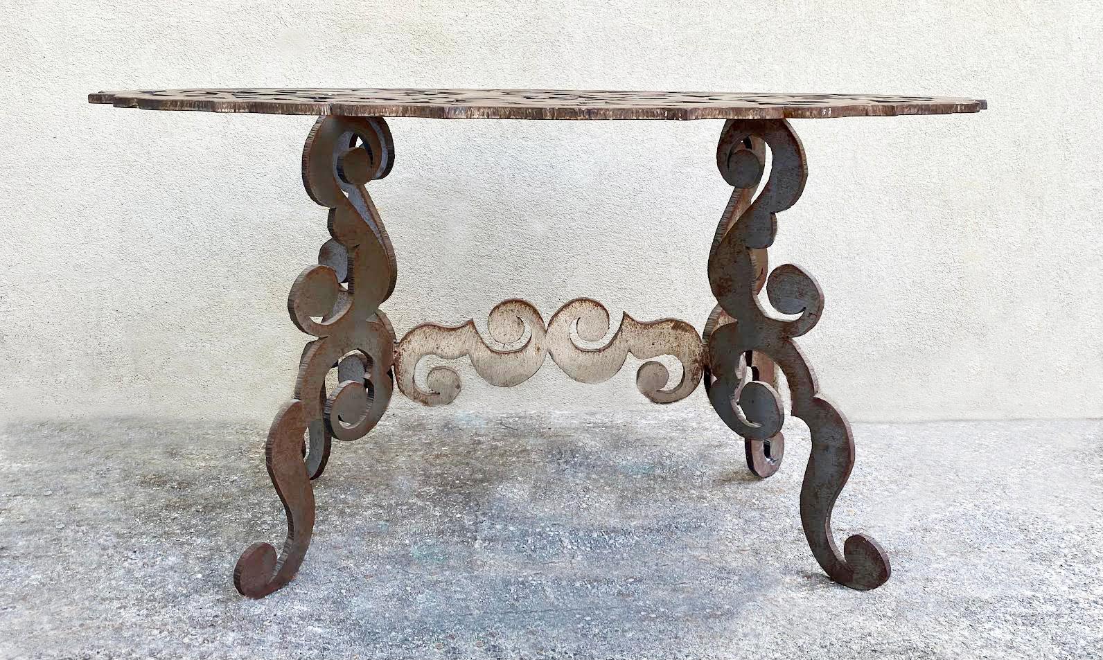 Eleva tu espacio con esta llamativa mesa central de acero de mediados de siglo, que exhibe una artesanía excepcional y un intrincado arte. El tablero ovalado presenta un diseño floral y de volutas bellamente recortado, con elegantes florituras,