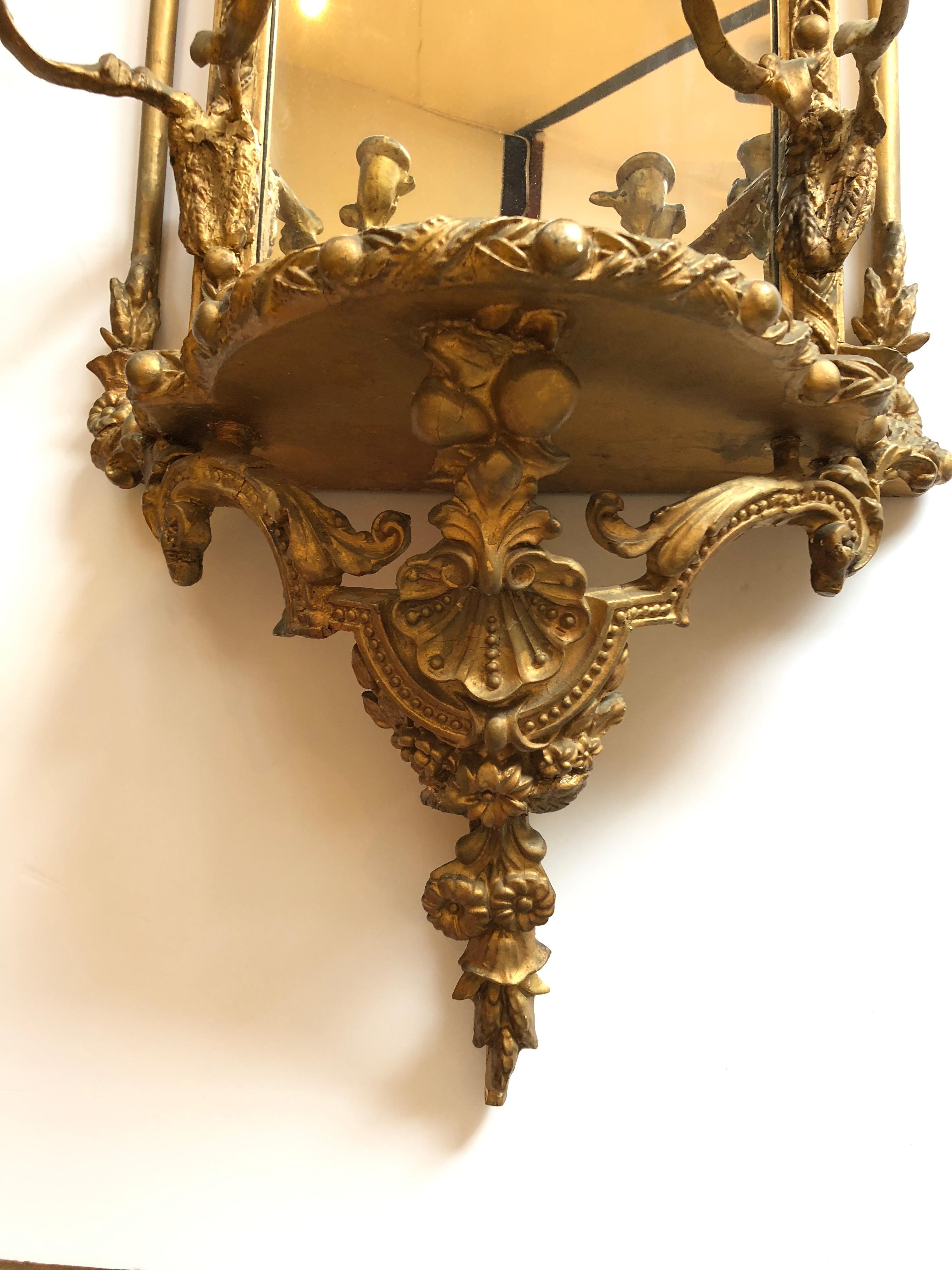 A lovely ornate French mirror having flowers, two candelabra with two candles each, a small protruding shelf, and intricate bow with eagle at the top. Has some losses and repairs, but a lot of character and charm for the price.