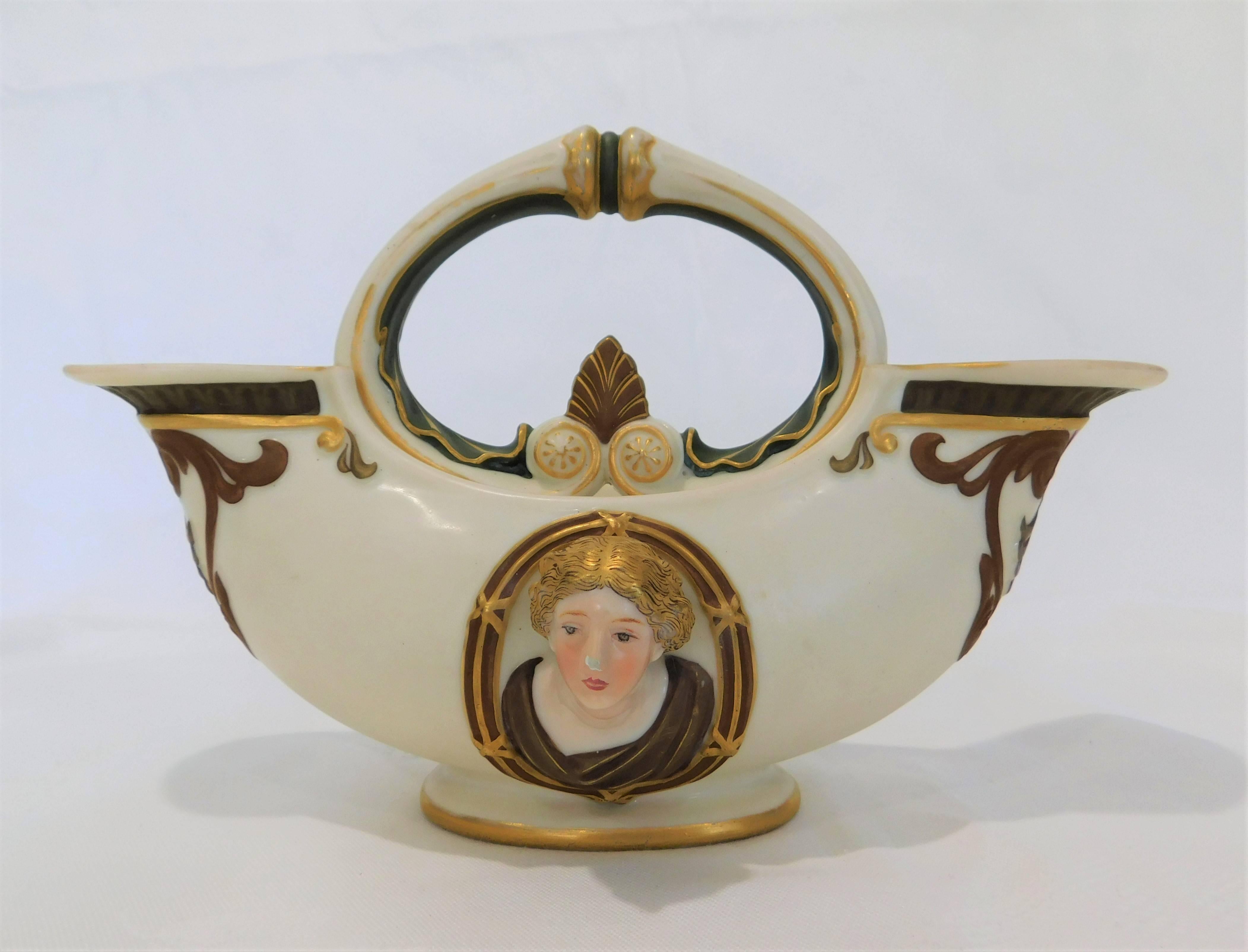 This ornate porcelain vase is in the shape of an archaic oil lamp. It has double heads and double spouts.