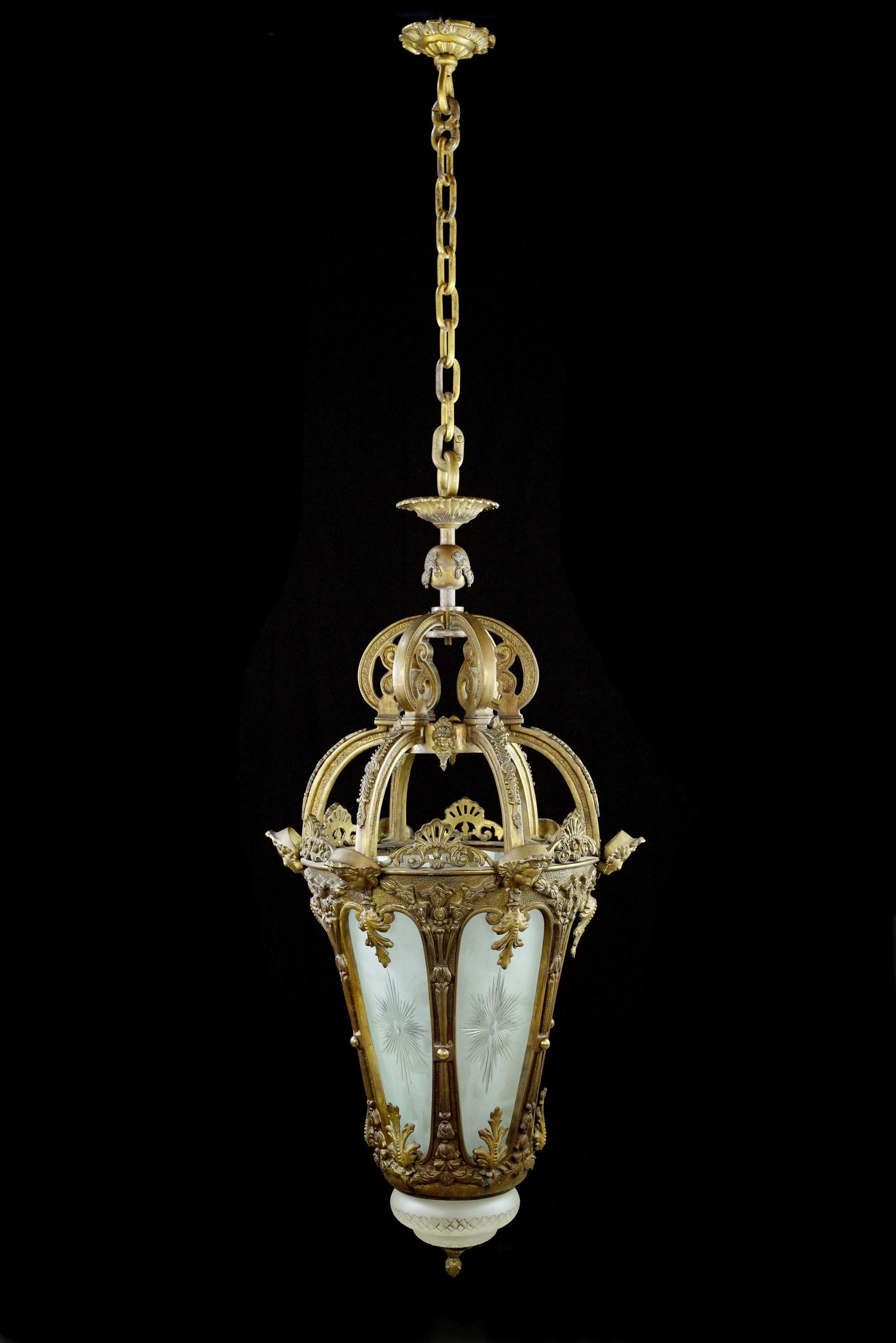 This French style highly ornate figural hanging lantern features intricate details in solid cast bronze. Its frosted and etched glass panels emit a soft and inviting glow, adding a touch of opulence to any space. Cleaned and restored. A true