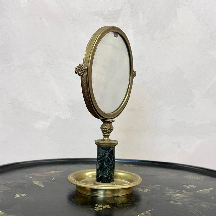 Miroir double face plaqué au mercure, bronze doré avec bord extérieur détaillé, assis sur une colonne de marbre.
Base à bords lisses, utile pour le rasage ou pour les bijoux sur une commode.
Légères rousseurs sur un côté de la plaque, comme illustré