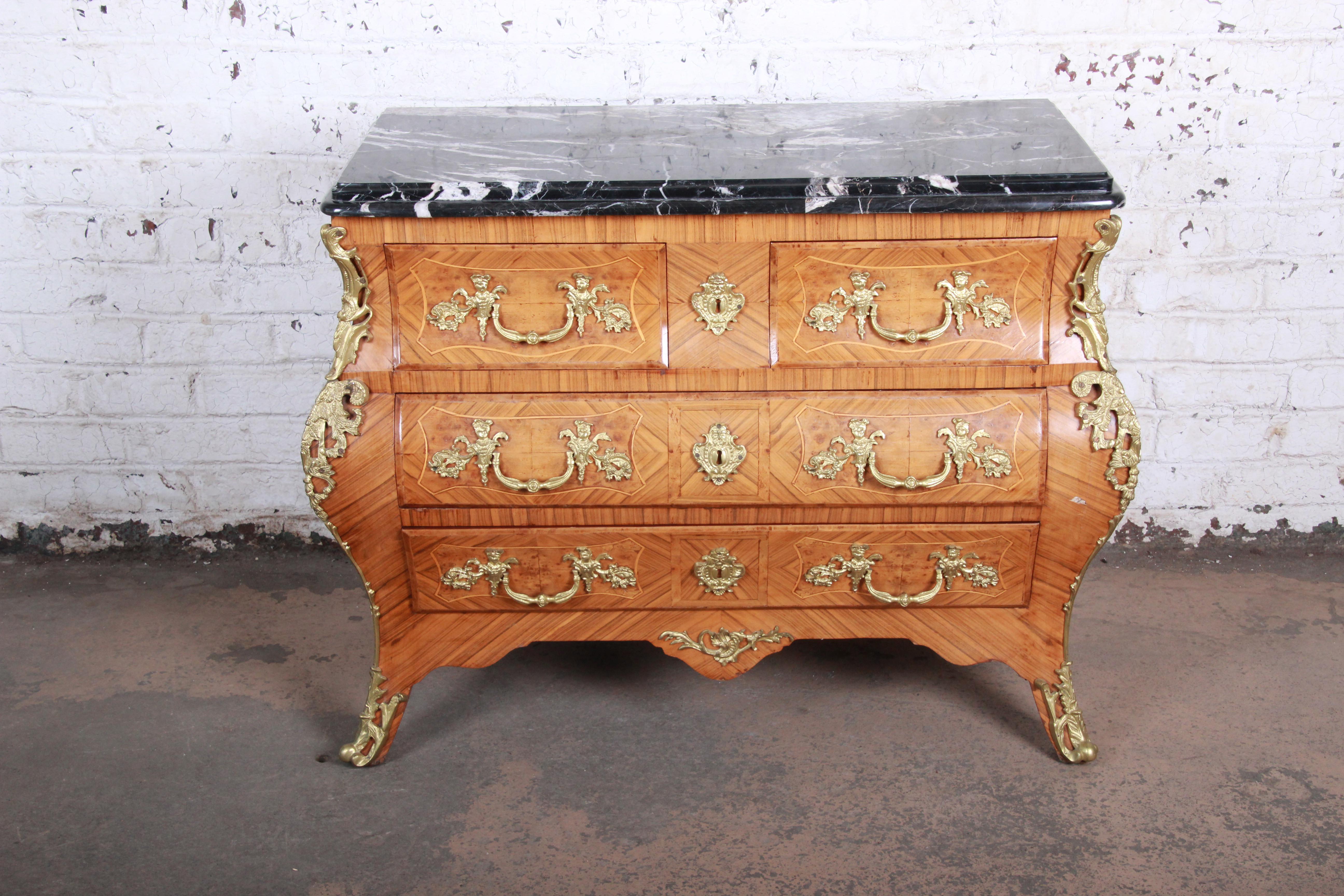 An exceptional French Louis XV style mahogany Bombay chest or commode. The chest features stunning mahogany wood grain with satinwood string inlays and inlaid burl wood. It has ornate mounted ormolu and an incredible 1.75