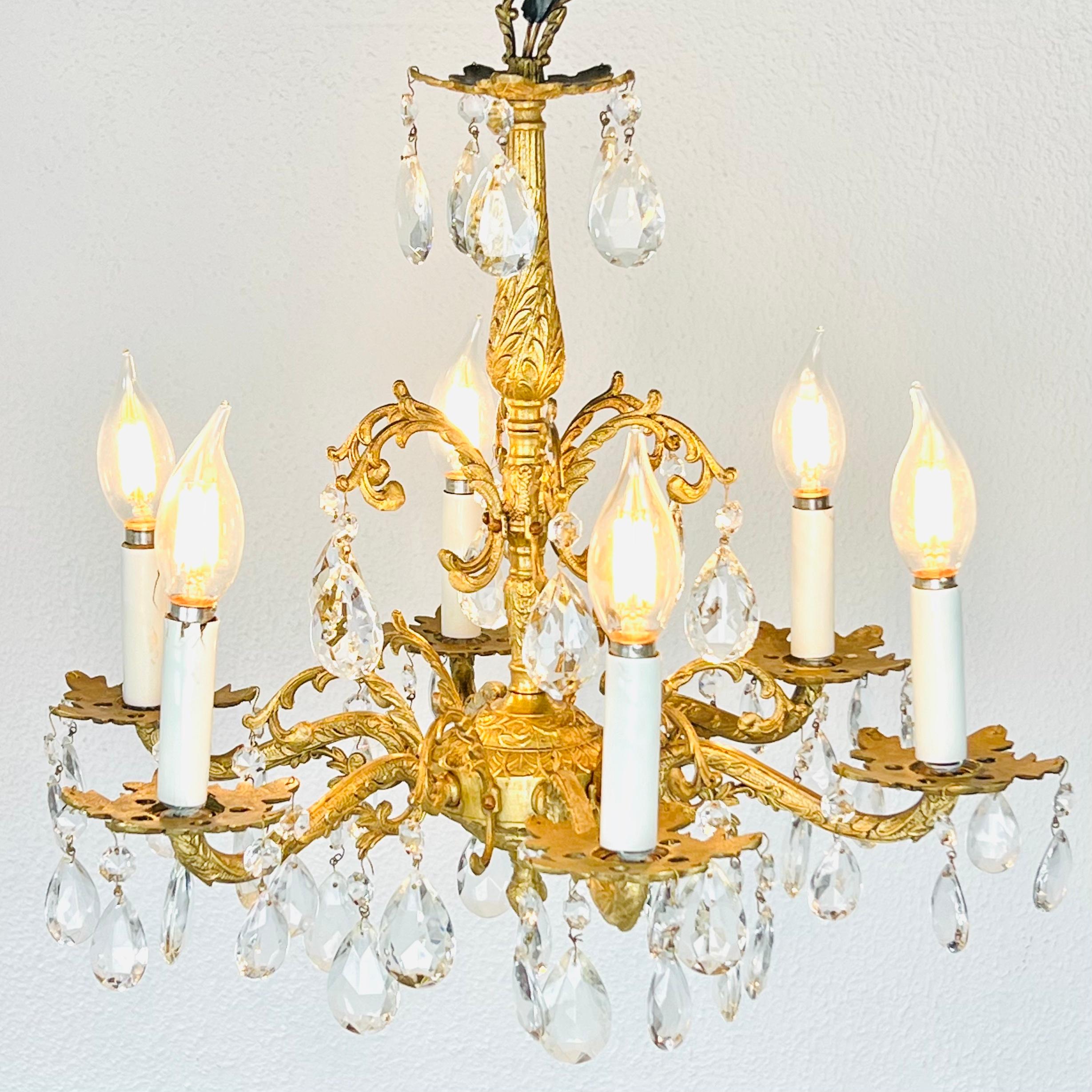 Lampadario a sei luci in ottone dorato e cristallo molato. Sei bracci di candele a spirale sono appesi a prismi a forma di pera. 
Buone condizioni con qualche lieve usura, come mostrato. 