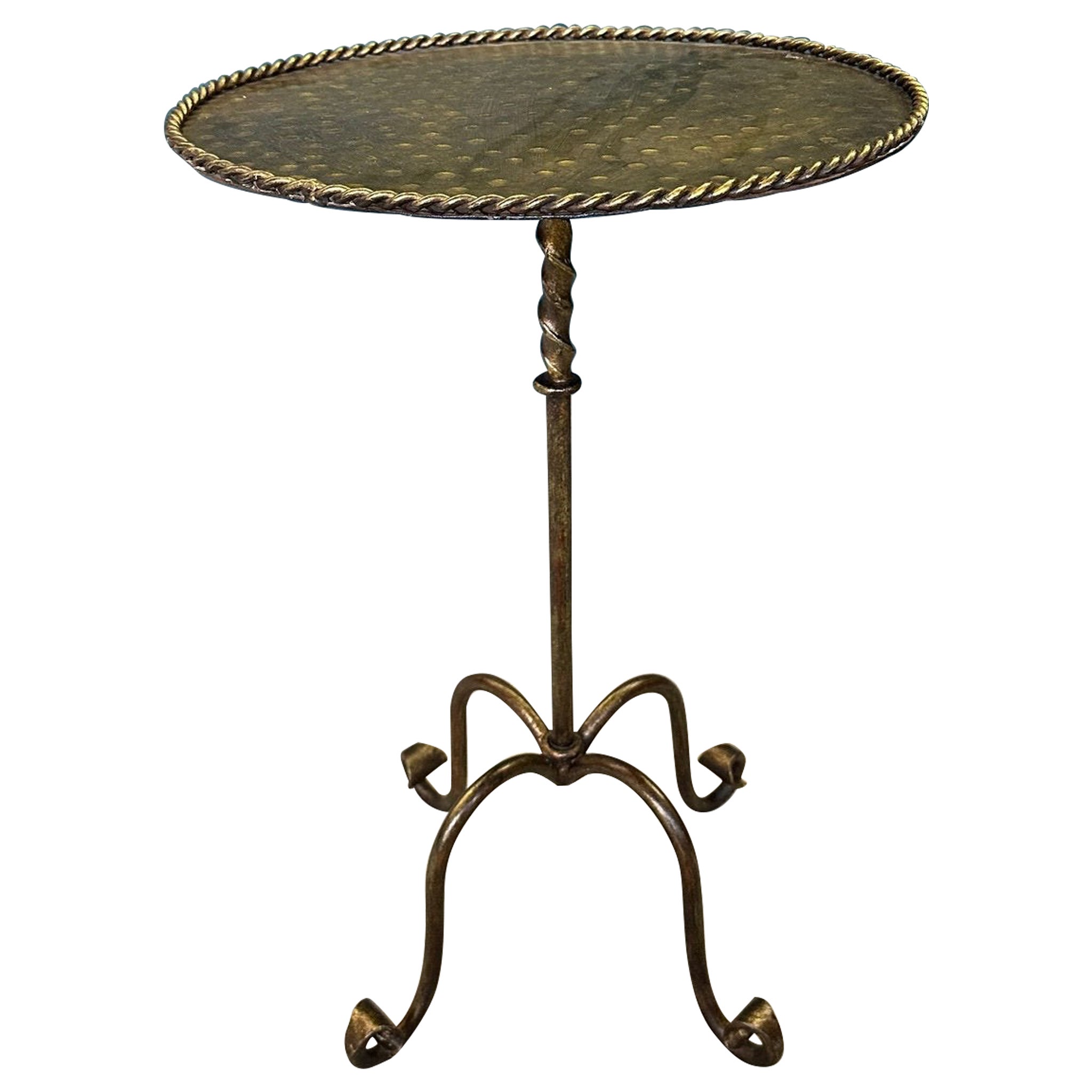 Mesa auxiliar ornamentada de hierro dorado con tablero martillado y patas con volutas