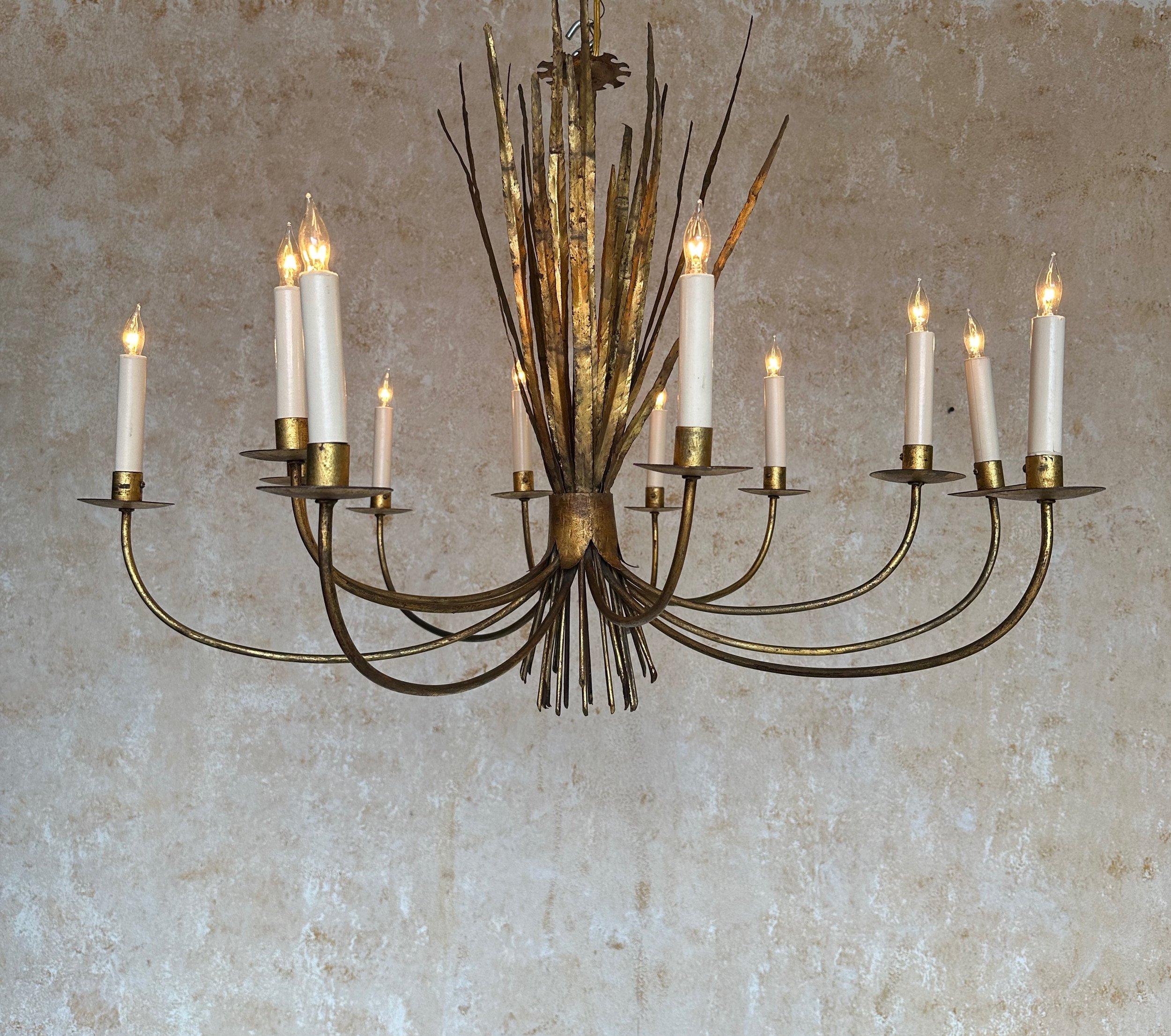 This unique 1940s Spanish gilt metal twelve-arm chandelier is stunning. This stunning 1940s Spanish gilt metal chandelier features twelve swooping arms emanating from a central stem adorned with delicate wheat grass fronds. The rich gilt patina is