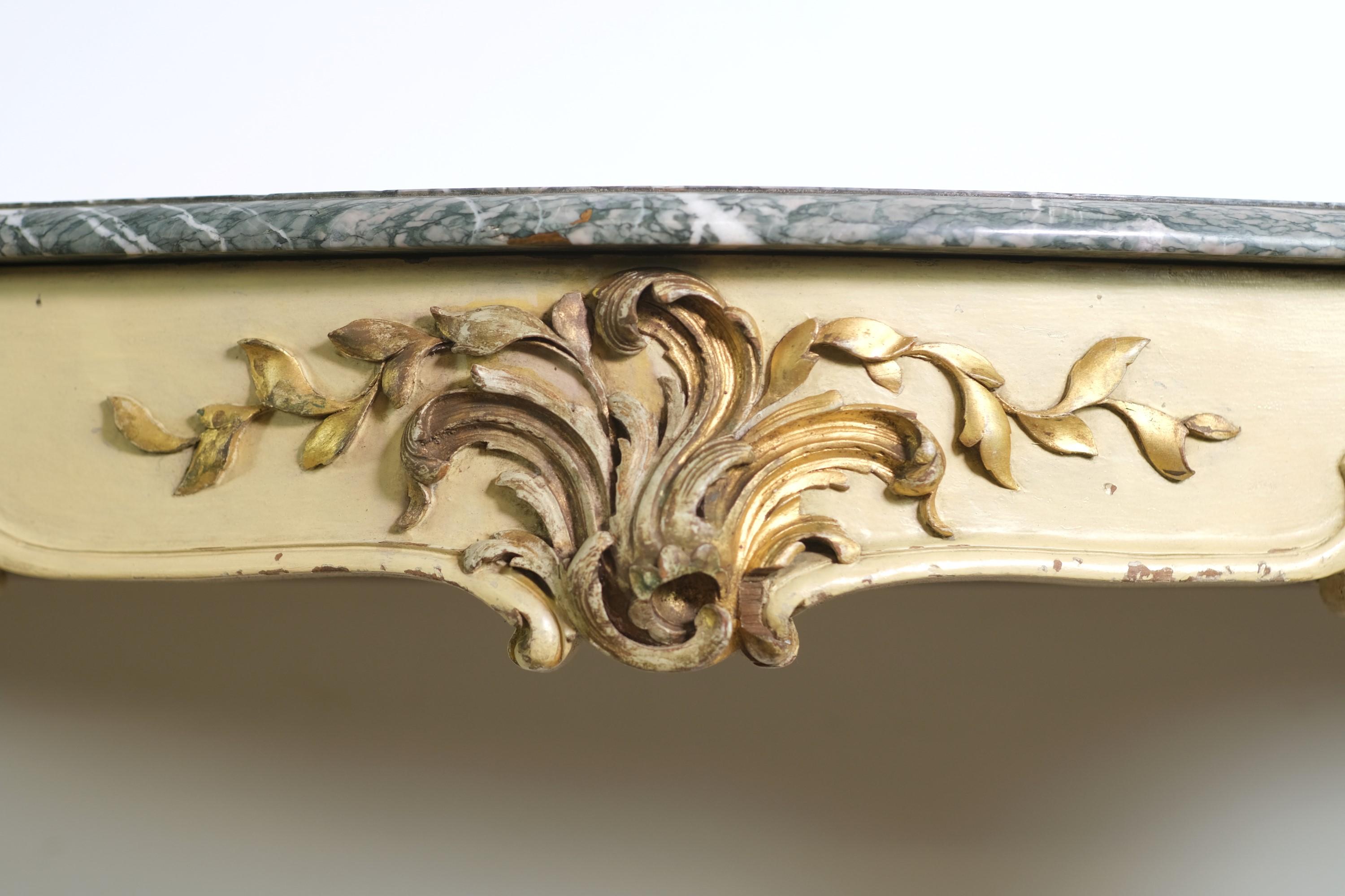 Rococo carved dark green marble top console table with gray and white veining and a carved cream and gold painted wooden base. 

Highly ornate Italian Rococo console table. The cream colored base is accented by hand carved gold painted floral