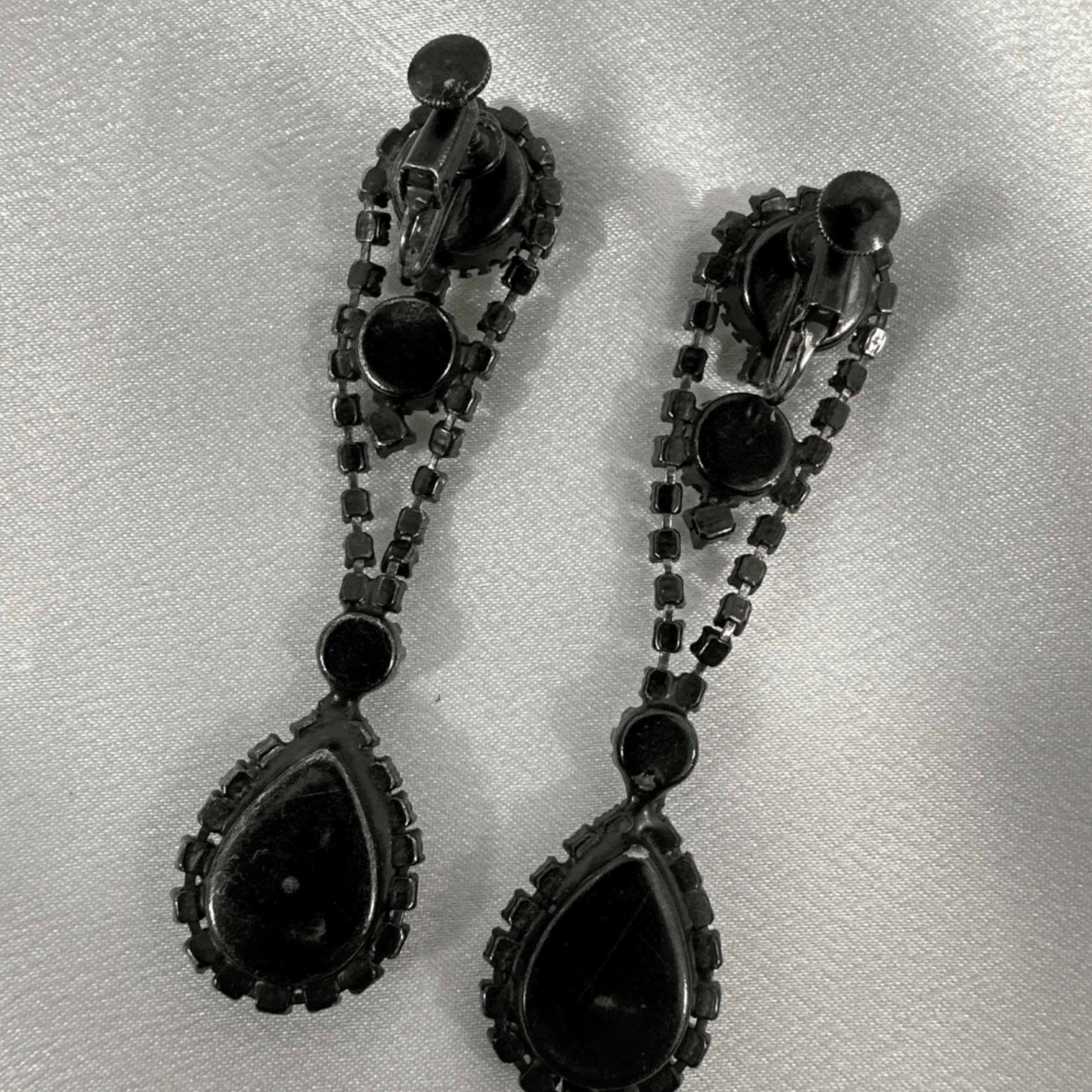 Rehaussez votre style vintage avec ces exquises boucles d'oreilles pendantes en japanis orné de pierres précieuses transparentes. Conçues avec des détails complexes et ornées de strass étincelants, ces boucles d'oreilles exsudent l'élégance et la