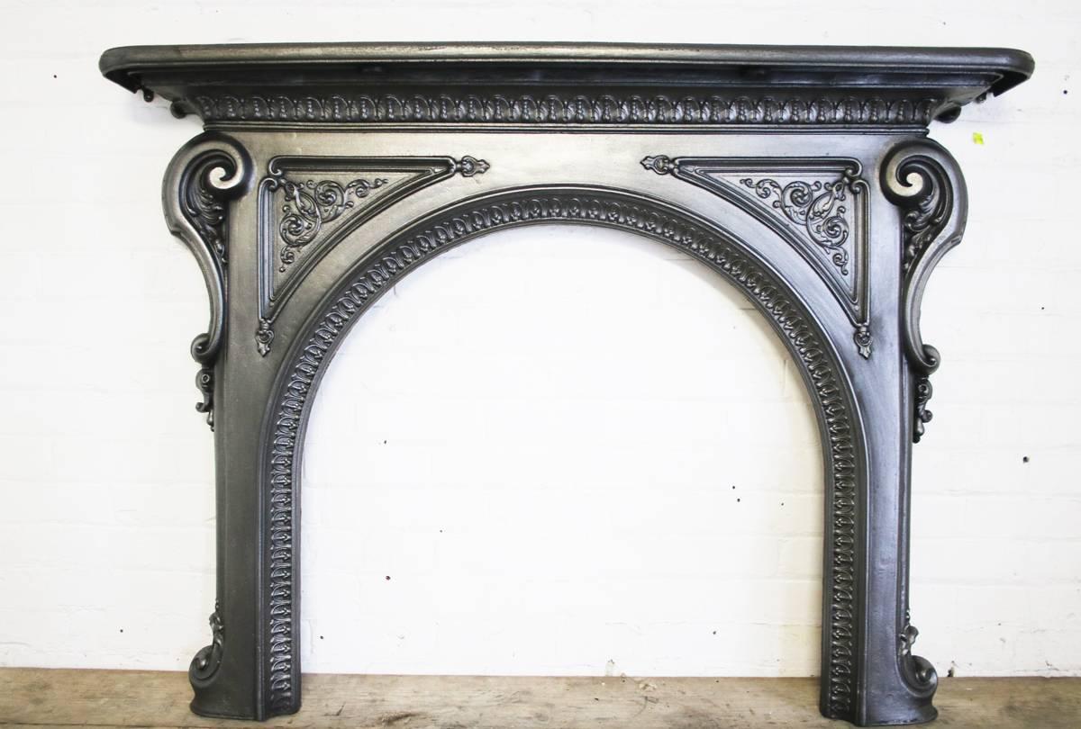 Ornate mid-19th century Victorian cast iron fire surround with arched aperture, circa 1870. 

Finished in traditional black grate polish giving a gun metal sheen.