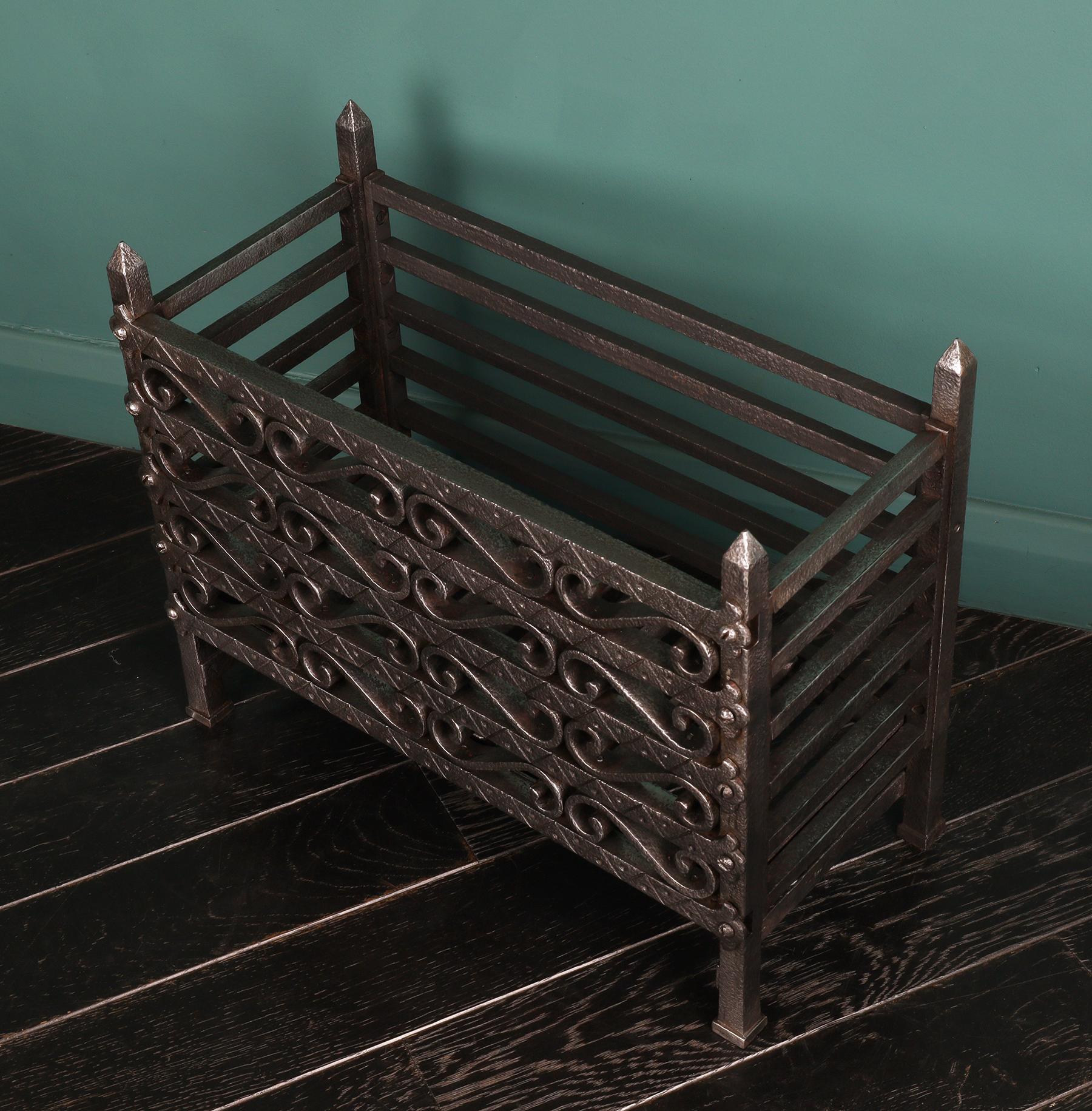 An ornate polished wrought iron fire basket intricately constructed with worked scrolls set between incised front fire bars. The rectangular blacksmith-made basket supported on plinth feet with pinnacle corner log-stops uppermost. Restored.
Height