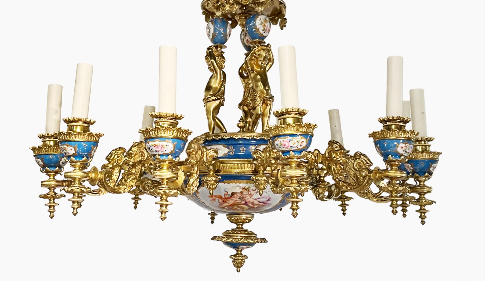 An antique Sevres style blue porcelain and ormolu Putti chandelier electrified with twelve candle lights. This ornate chandelier features a central baluster modeled after with three putti in gilt bronze with stylized anthropomorphic arms. Each light