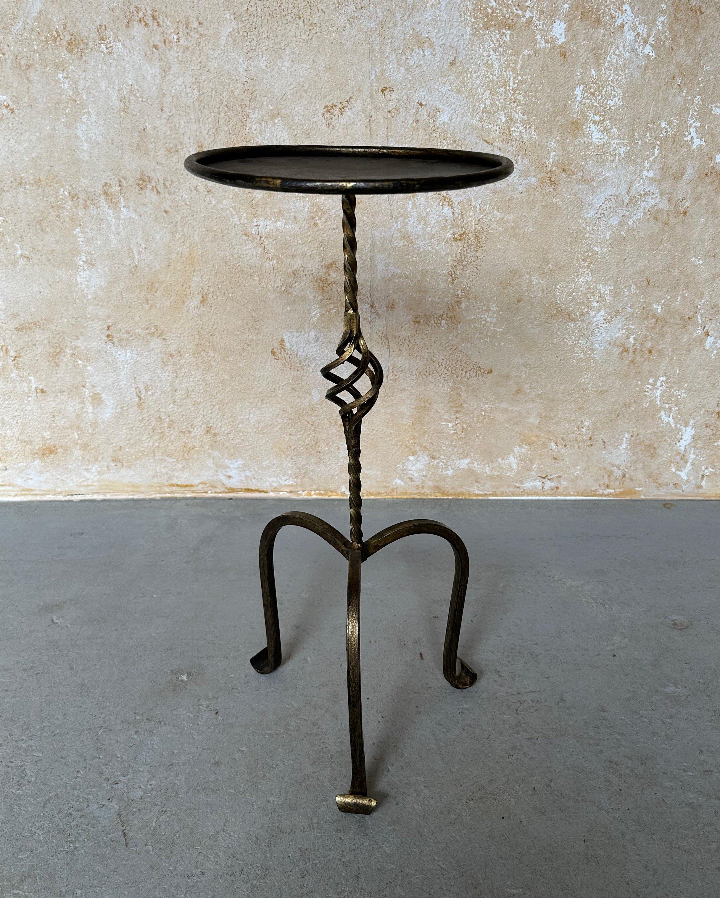 This highly decorative Spanish drinks table was recently hand crafted by skilled European artisans using traditional iron-working methods. It features a twisted stem with an ornate central decorative element mounted on an elevated tripod base with