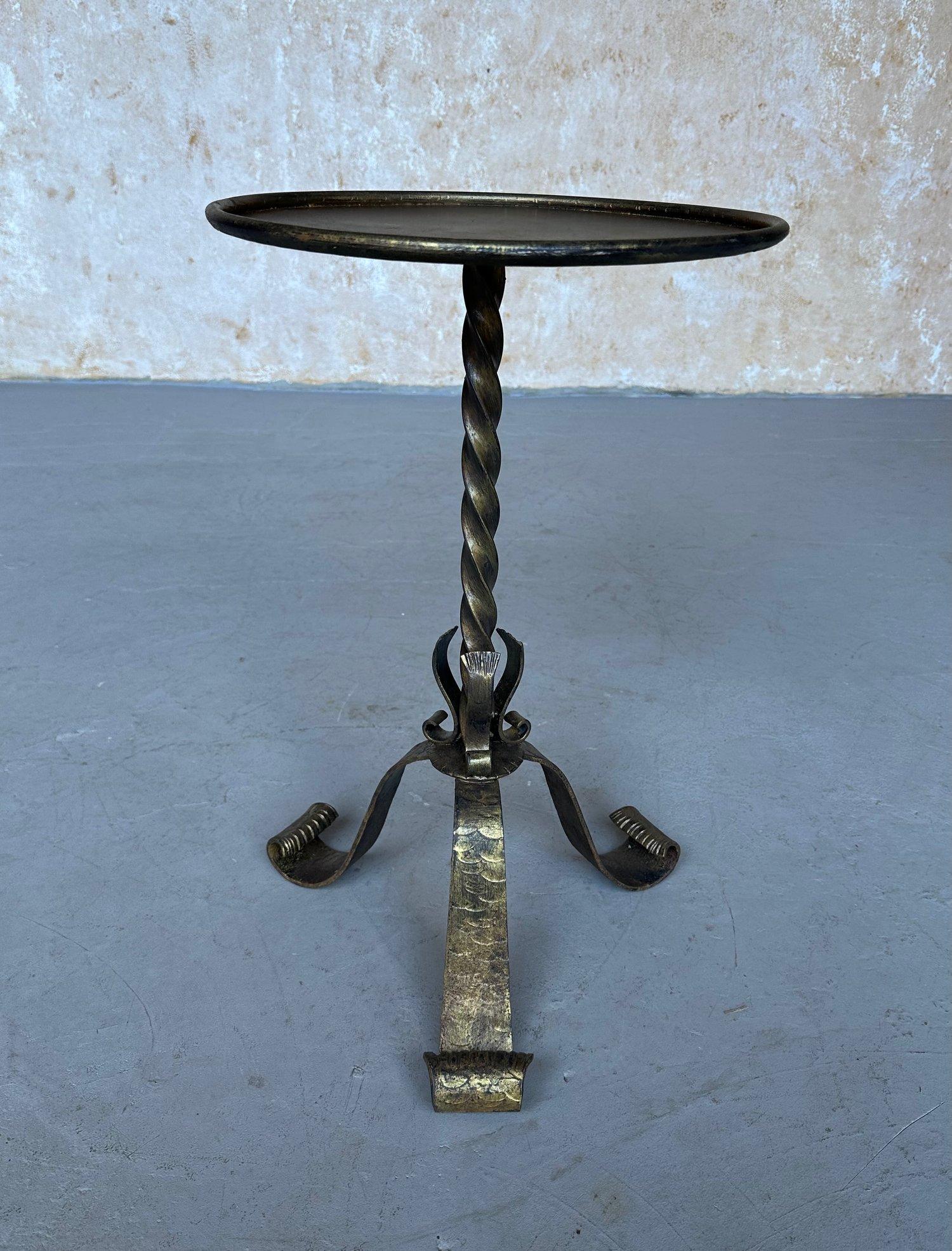 This elegant Spanish iron drinks table was recently hand-crafted by skilled European artisans using traditional iron-working techniques. It features a robust twisted central stem resting on an elaborate tripod base with gracefully scrolled hammered