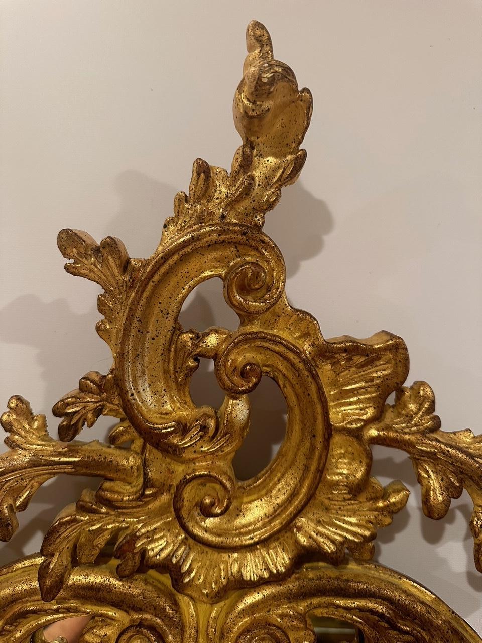 Beautiful ornate Venetian style gilded mirror having curlicues and bottom feet.  Hand carved gilt wood by Decorative Crafts.
