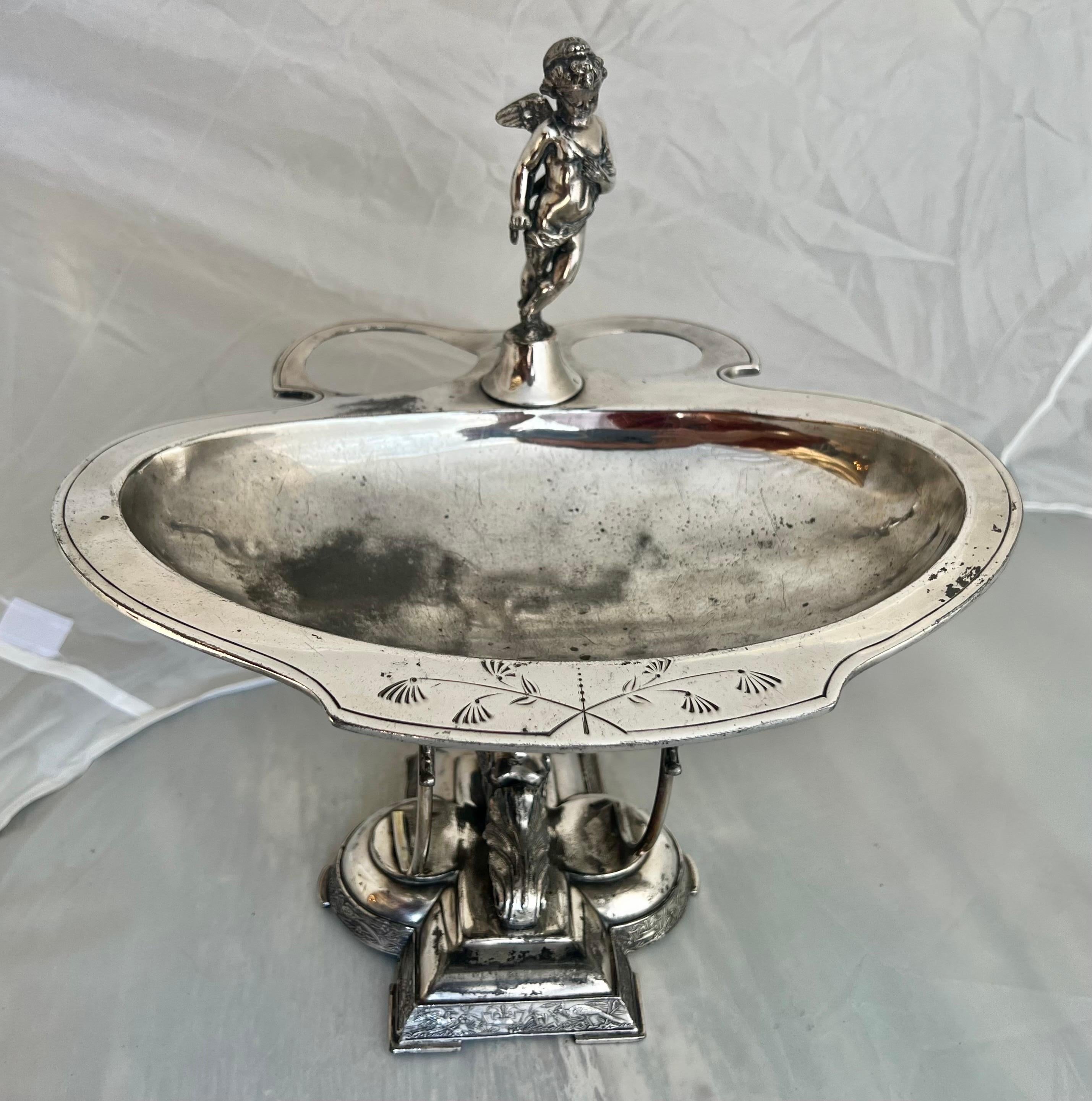 The Wilcox Silver Plate serving dish features a finely detailed angel and winged figure adornments along with acanthus leaf motifs.  The etched pheasants and foliage around the base add a touch of natural elegance. 
This piece likely reflects both