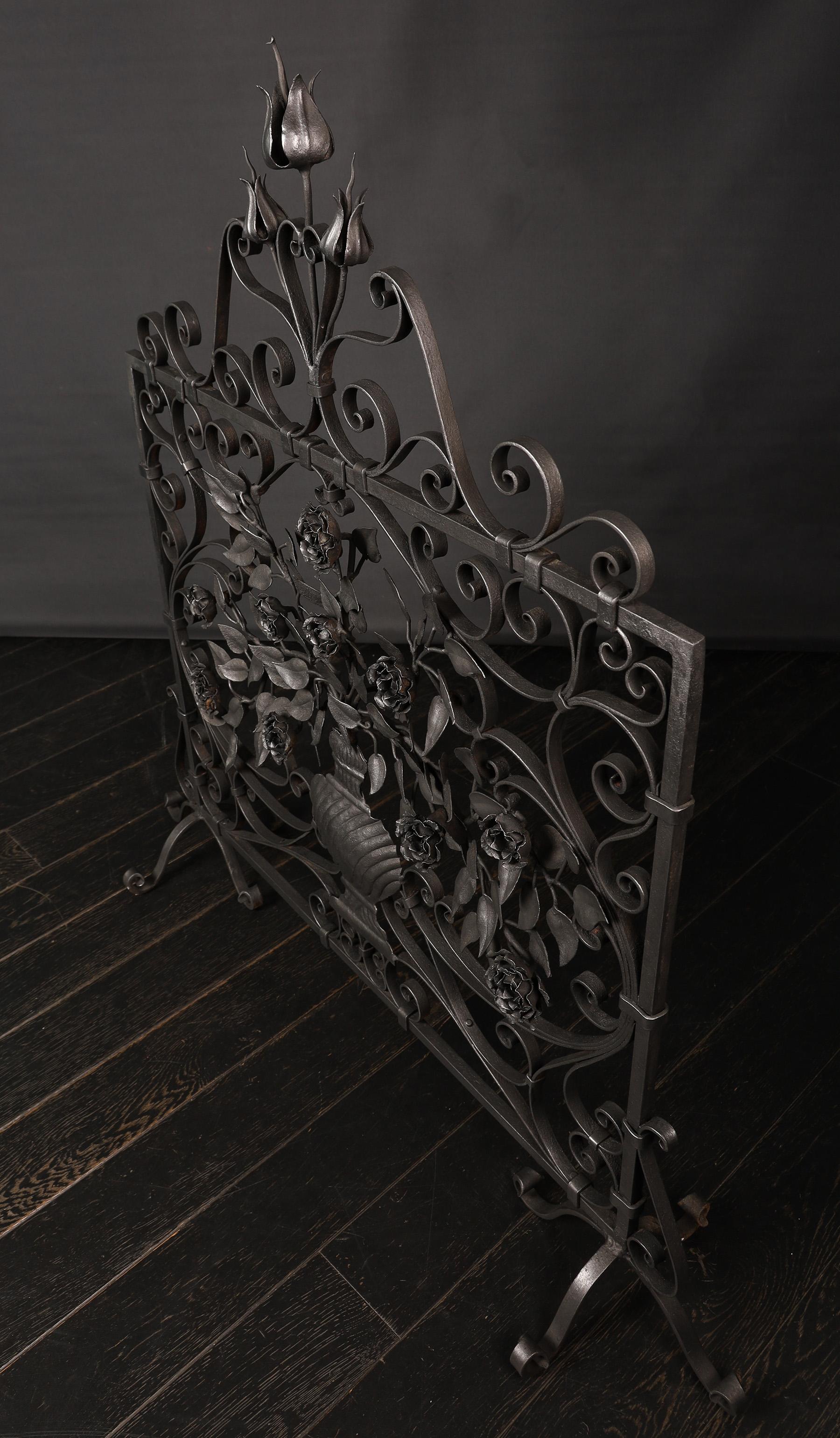 Un écran de cheminée en bois ouvragé orné de roses et de tulipes. Le vase central nervuré abrite le feuillage et les roses aux formes exquises, encadrées par des rinceaux, le tout sur des supports à volutes arquées. De belles tulipes ouvragées sur