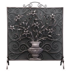 Écran de cheminée orné de volutes et de fleurs sauvages en fer forgé