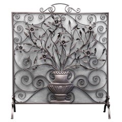 Pantalla de forja ornamentada con volutas y flores silvestres