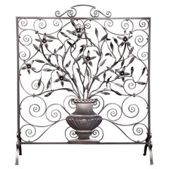 Écran de cheminée orné de volutes et de fleurs sauvages en fer forgé