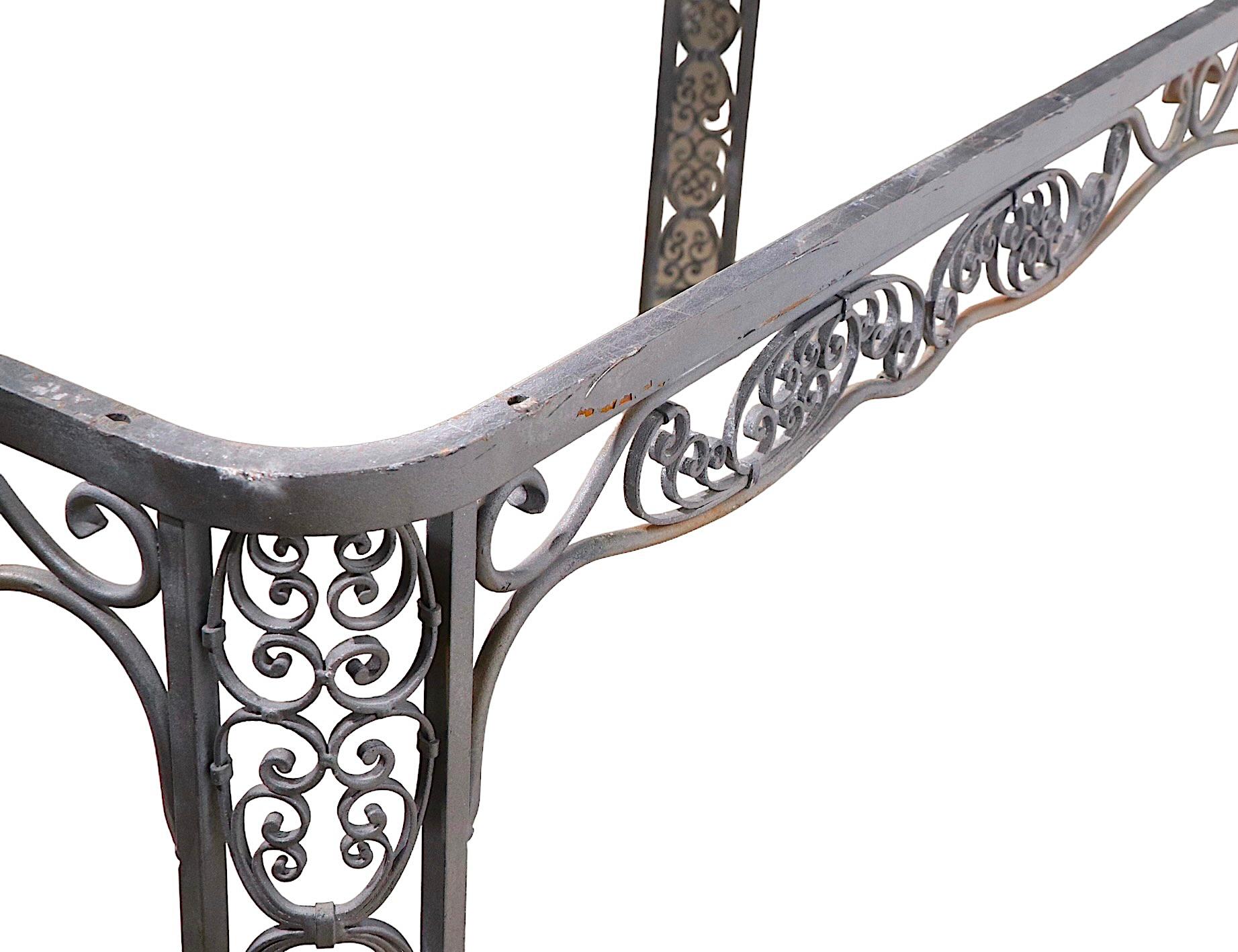 Stunning ornate wrought iron dining table b y Lee Woodard. The table features rounded corners, each having two legs, with elaborate scrollwork throughout the entire table frame. Charming and romantic without becoming saccharine or trite. This