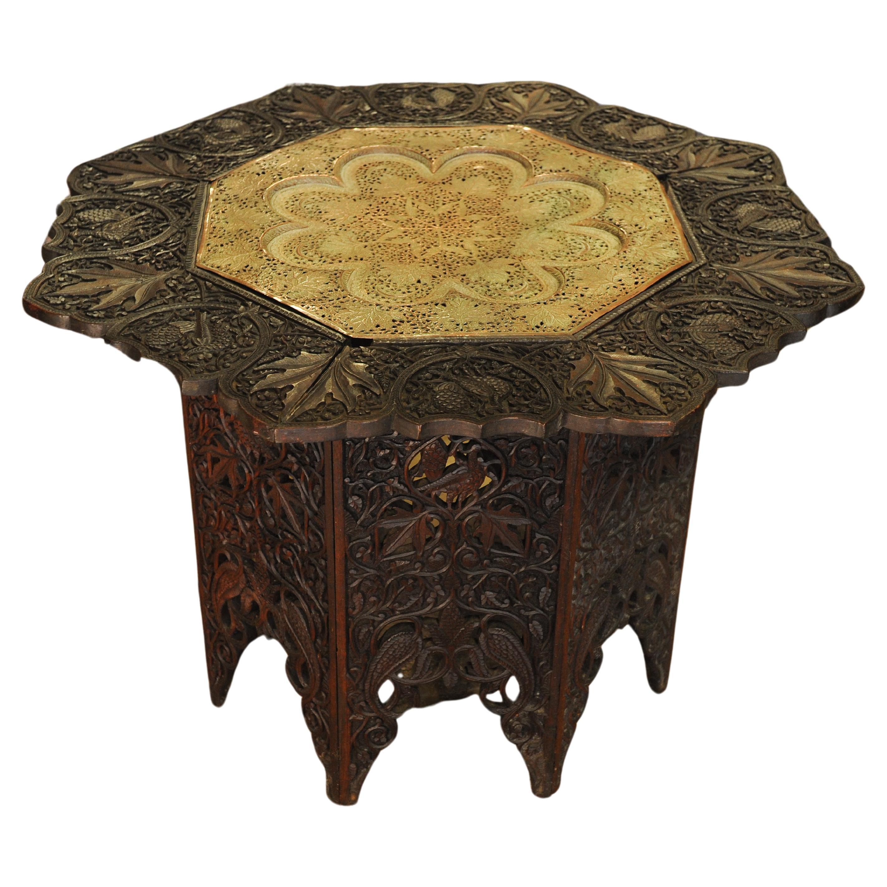 Asian octagonal occasional table on folding base, with brass insert and all-over carved and pierced decoration.
Intricately carved with nature inspired elements: leaves, birds, trees

Table base folds and table top, and brass insert lifts off all