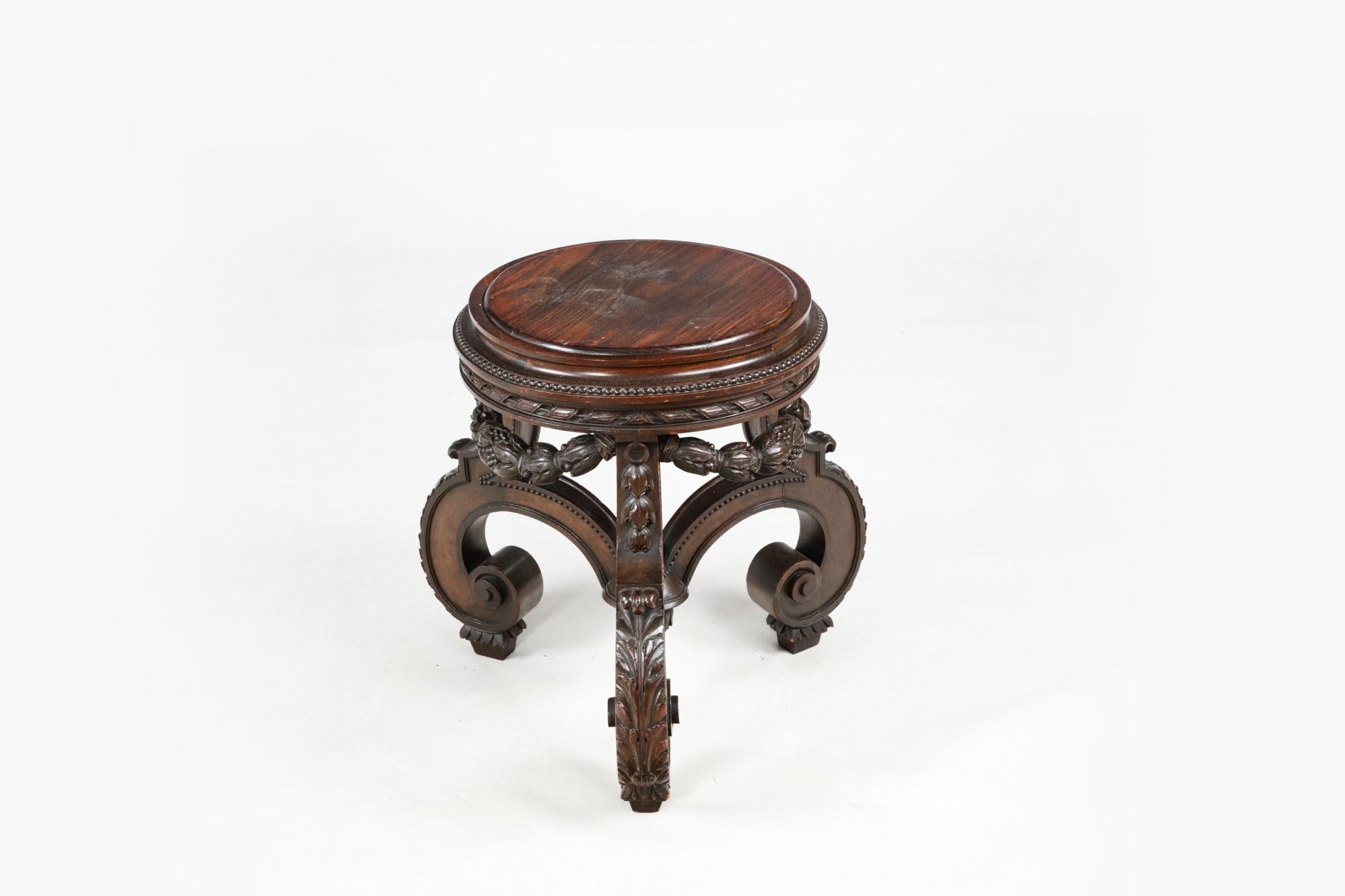 Ornately carved Chinese cherrywood pot stand, circa 1880. The carved and pierced hardwood frame sits below a dark brown circular hardwood top. The richly carved and pierced apron features ornate vine motifs. All raised on cabriole legs, carved in