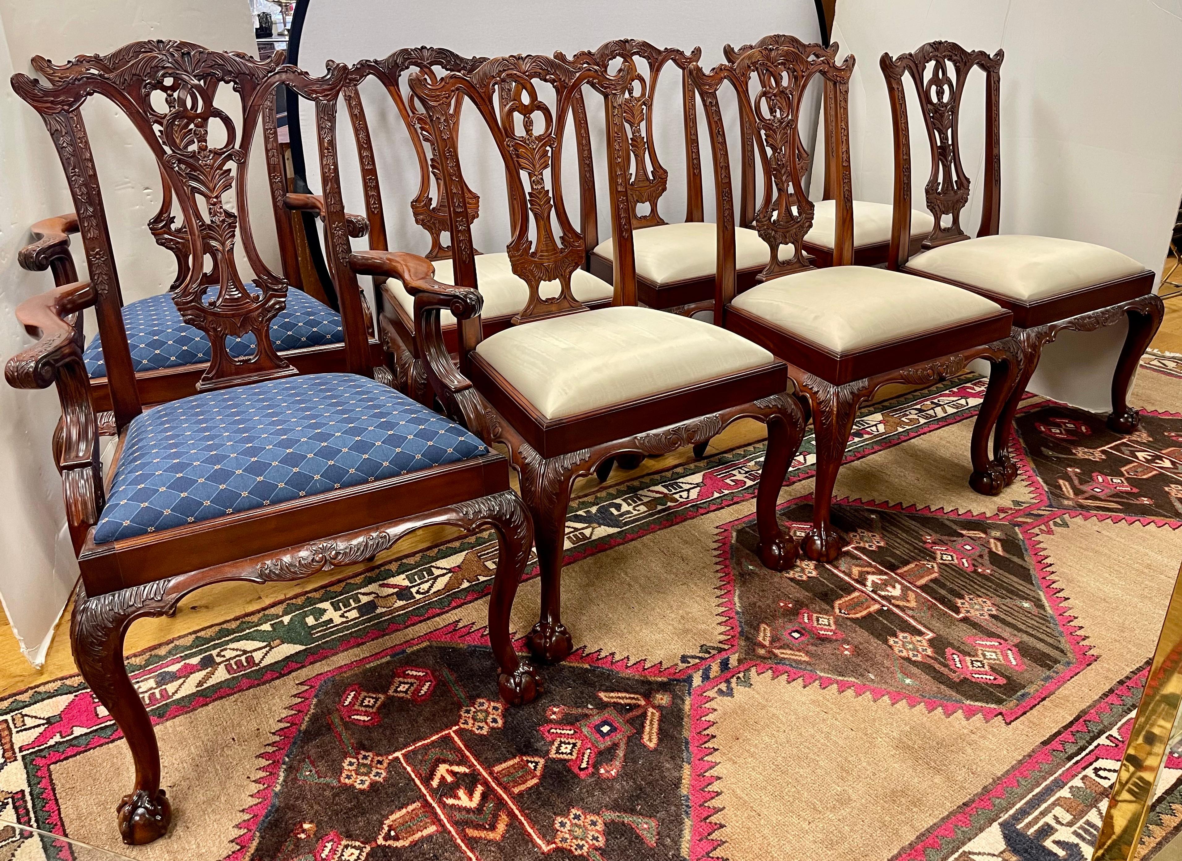 Elegant and ornately carved set of Chippendale style mahogany dining room chairs. Eight in all with two being armchairs and six side chairs. The side chairs have a silk neutral upholstery and the armchairs a luxurious blue color scheme. Minor