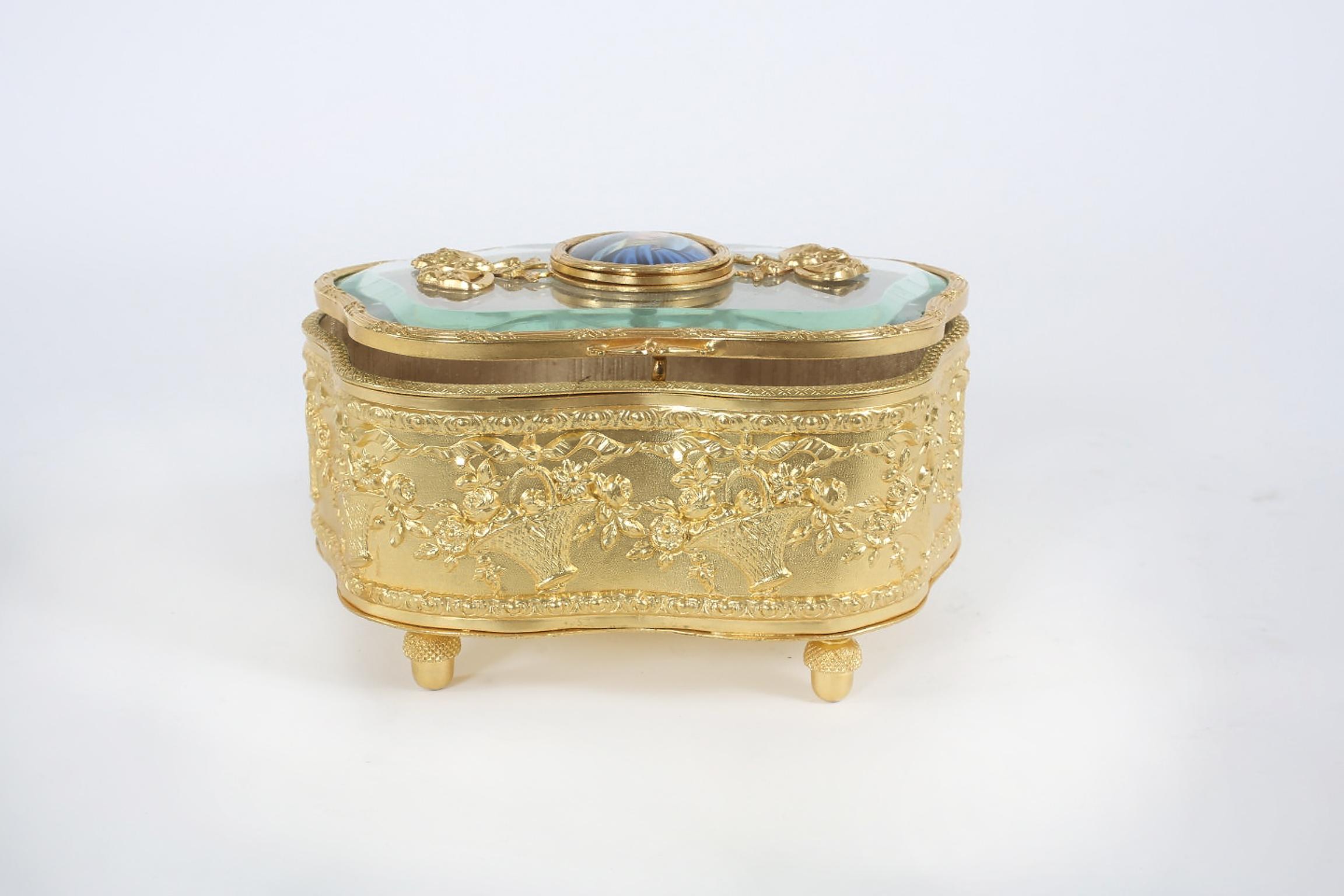 Ornately gilt gold decorative footed vanity box with central plaque of Madonna on the glass lid cover & gold fabric interior. The box is in great vintage condition. Minor wear consistent with age / use. The box stand about 6.25