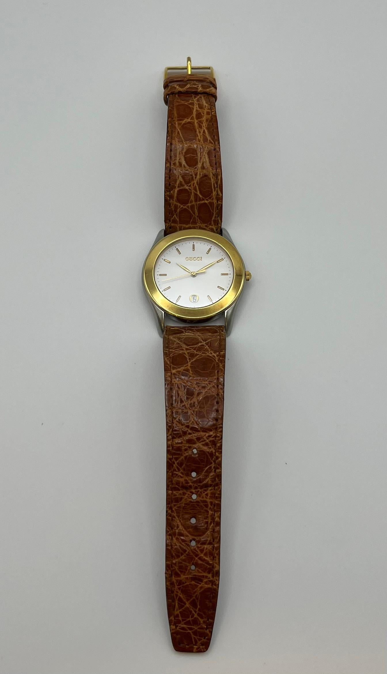 Este fino reloj de pulsera vintage de Gucci procede directamente de la década de 1980, como se desprende de su diseño clásico e intemporal. La caja mide 35 mm de diámetro y es de acero, mientras que el bisel es de oro amarillo macizo de 18 quilates.