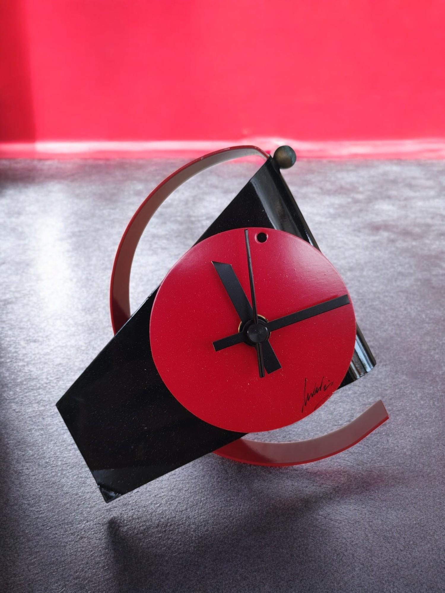 Radical Memphis style table clock, produced in the early 1980s, postmodern, made of lacquered metal, with red circular dial on black background. Signature 