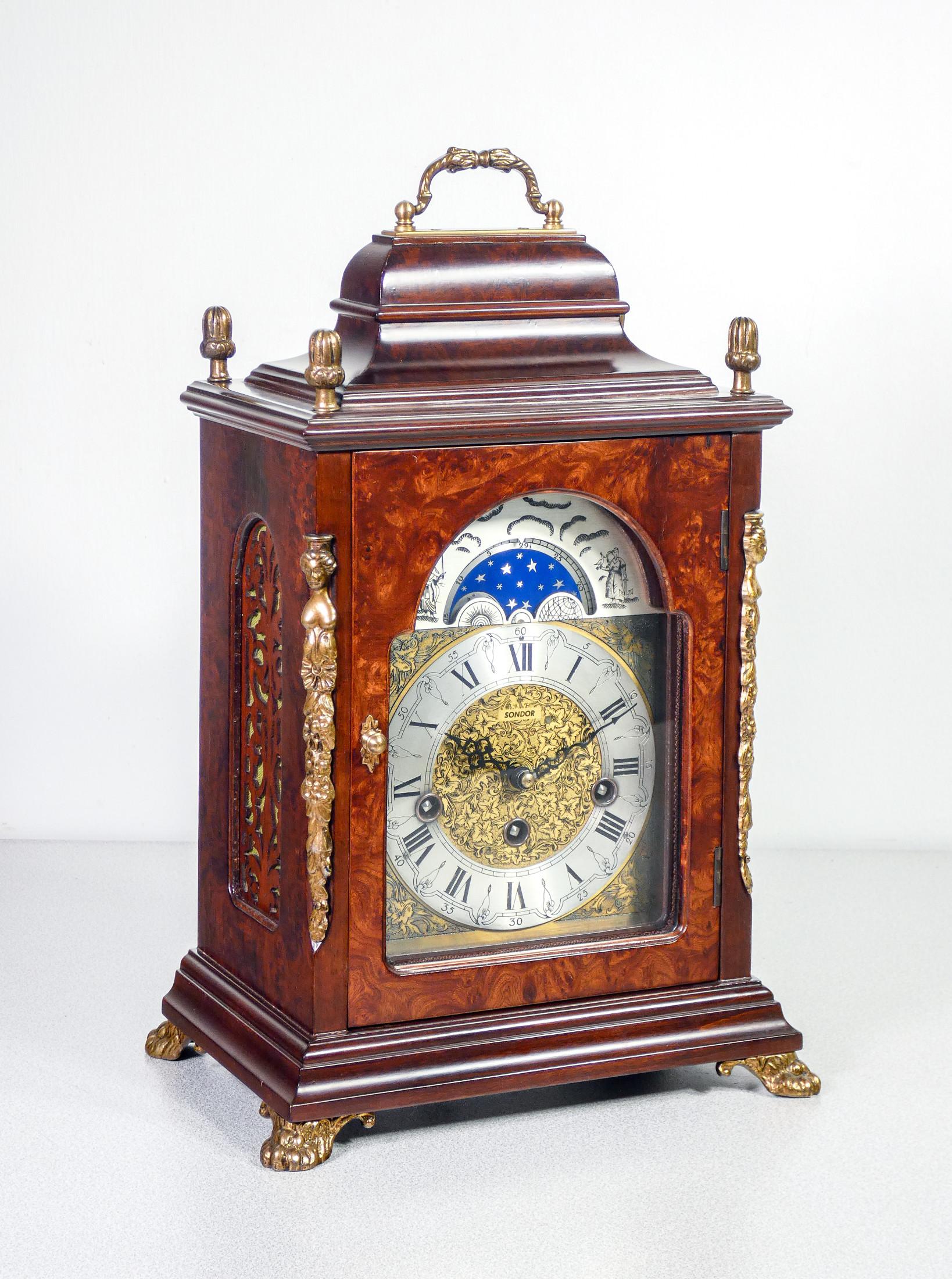 Orologio da tavolo
SONDOR
FHS-Bewegung
Franz Hermle Sohn
con fasi lunari
e suoneria
Westminster ai quarti.

ORIGINE
Germania

PERIODO
Anni 70

MARCA
Orologio Sondor con movimento FHS Franz Hermle Sohn

MATERIALI
Struttura in legno.
