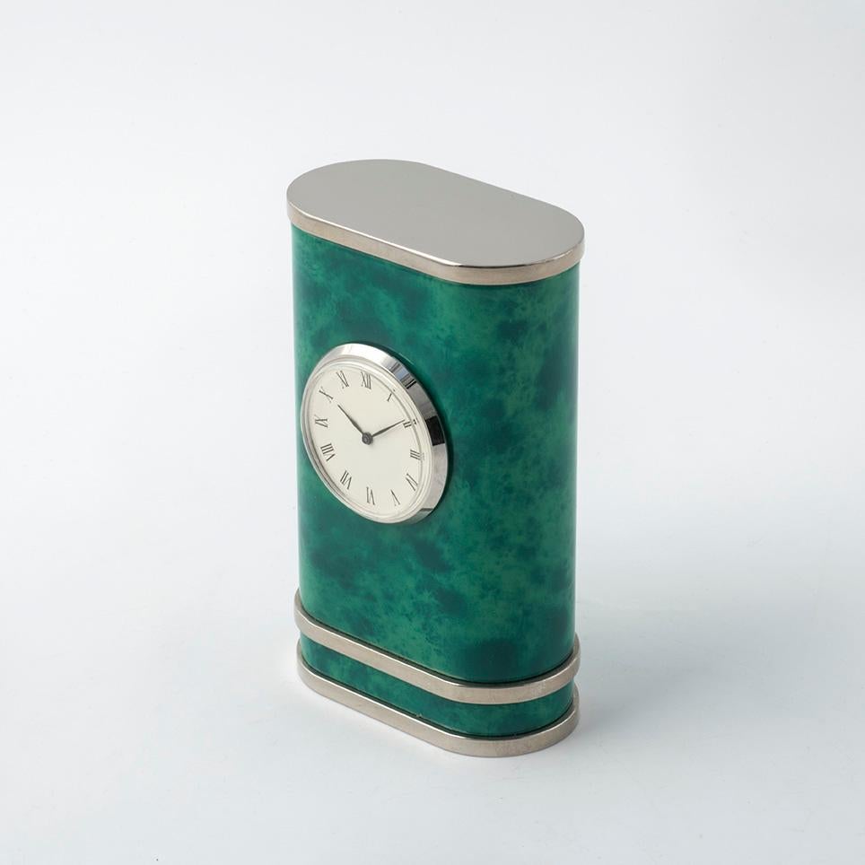Fa parte della Collezione LE LACCHE disegnata da  Nino Basso questo raffinato orologio da tavolo dalla linea arrotondata  e seducente texture nuvolata  intercalata da  particolari  nichelati. 
Il suo design  lineare e compatto ne fà un oggetto