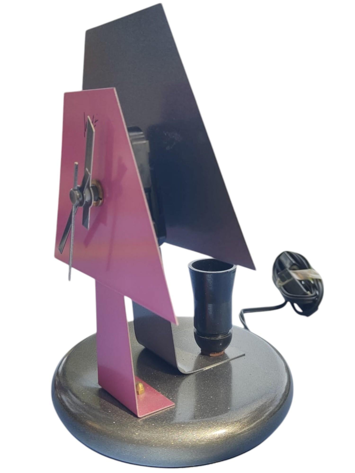 Eine Tischlampenuhr im Stil von Radical Memphis, hergestellt in den frühen 1980er Jahren, postmodern, aus lackiertem Metall, mit einem roten lampenförmigen Ziffernblatt auf schwarzem Hintergrund. Signatur 'Missiani' auf dem Zifferblatt