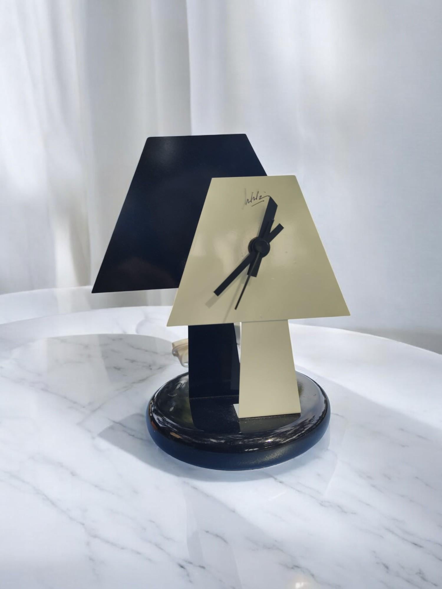 Orologio lampada da tavolo in pieno stile Radical Memphis, prodotto agli inizi degli anni '80, postmoderno, realizzato in metallo laccato, con quadrante bianco a forma di lampada su sfondo nero. Firma 