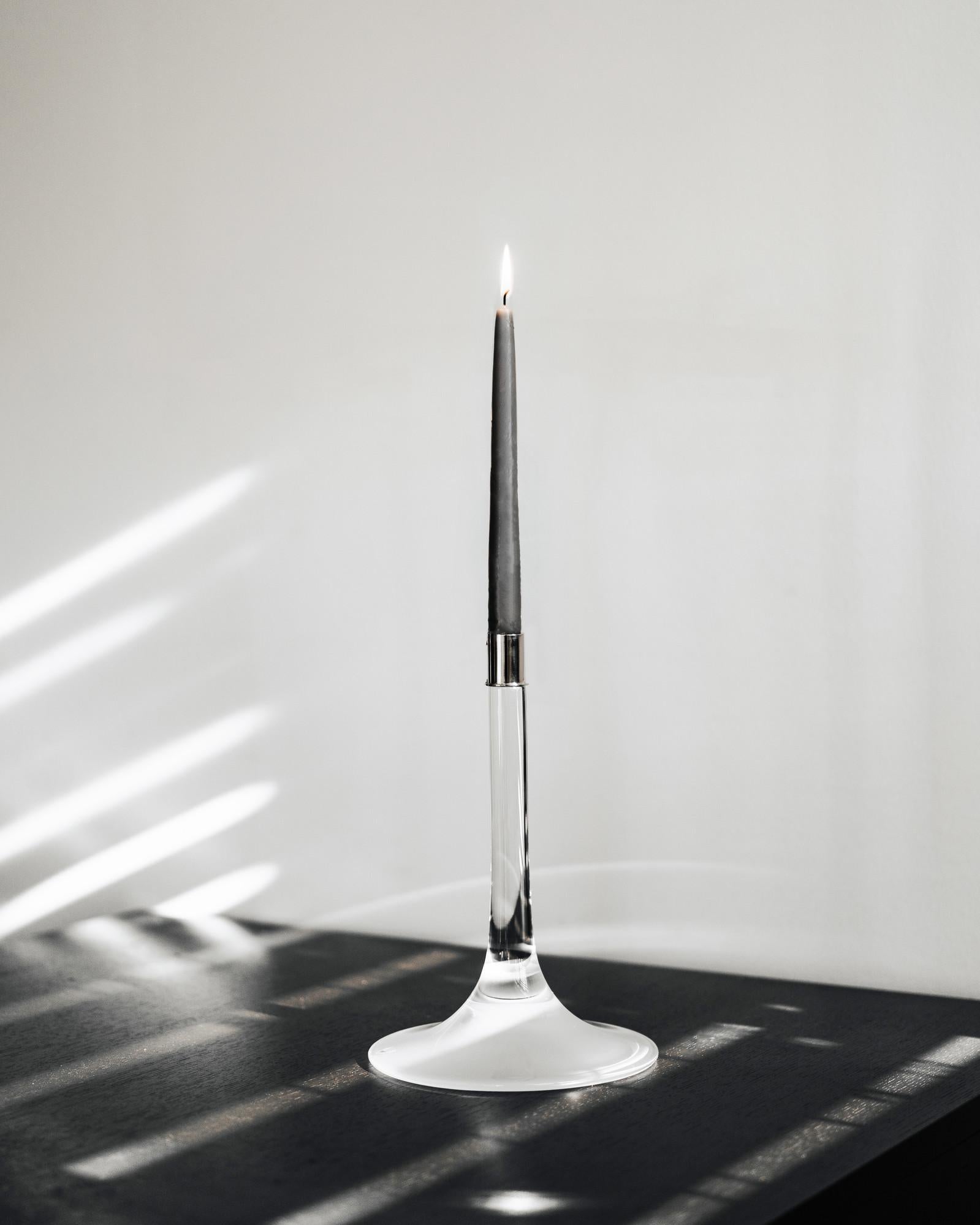 Cirrus Candlestick Tall di Orrefors è un candeliere con un'ampia base, un elemento distintivo che contribuisce alla sua identità. La base con la parte inferiore sabbiata offre una transizione morbida verso l'asta di cristallo trasparente, che