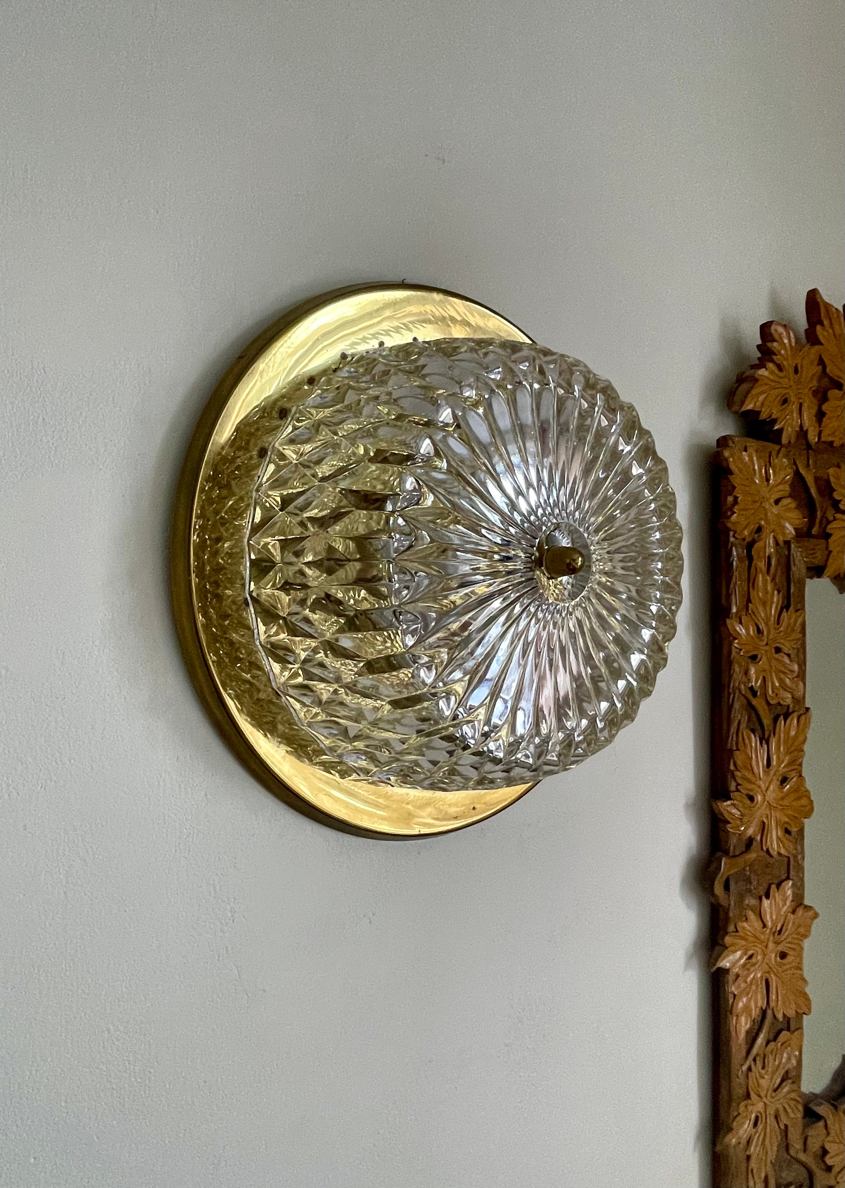 Scandinavian midcentury modern wall sconce manufactured by Orrefors and Lyfa in the 1960s. Circular textured art glass on shiny brass plate mount. Beautiful vintage condition. 
Rewiring upon request - local rewiring recommended. 
Denmark/Sweden,