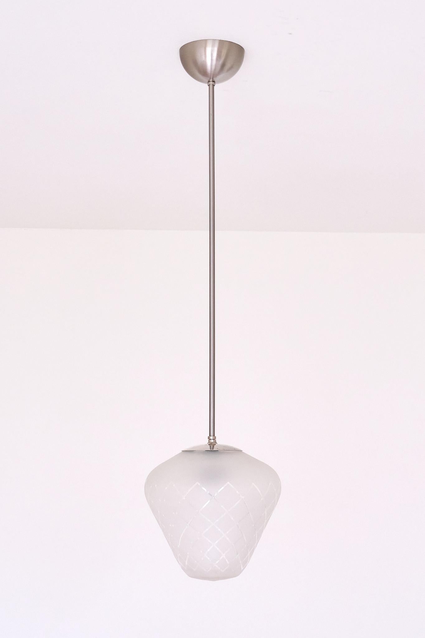 Cette étonnante suspension en verre a été produite à Orrefors, en Suède, dans les années 1950.

Le design présente un abat-jour en verre sablé de couleur blanc givré mat et translucide. Le motif géométrique en damier placé en diagonale a été découpé