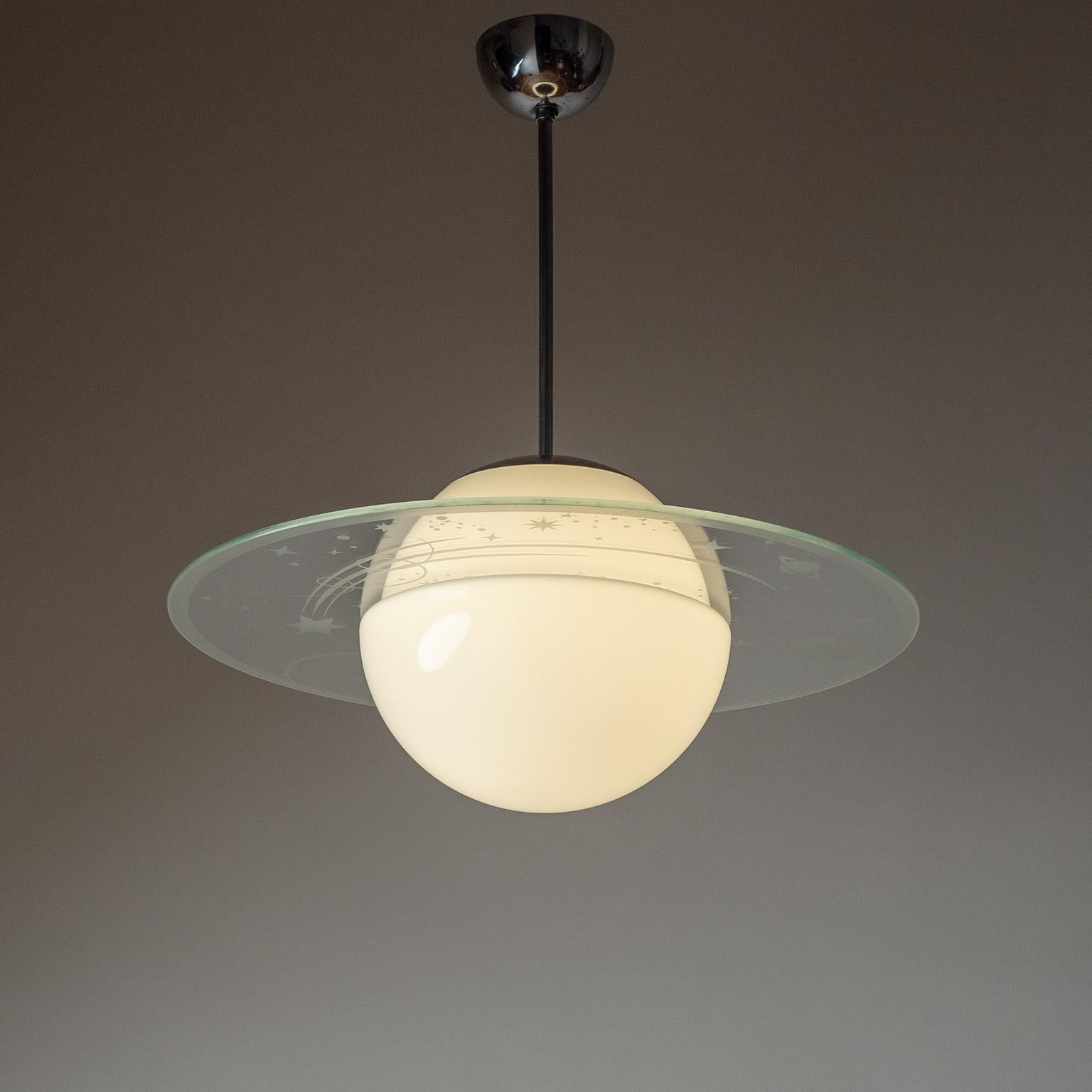 Raro colgante Orrefors Saturnus de la década de 1940. Globo de cristal opalino con un gran disco Saturno de cristal transparente con una bonita decoración serigrafiada de un cielo estrellado. Muy buen estado original con algo de pátina en los