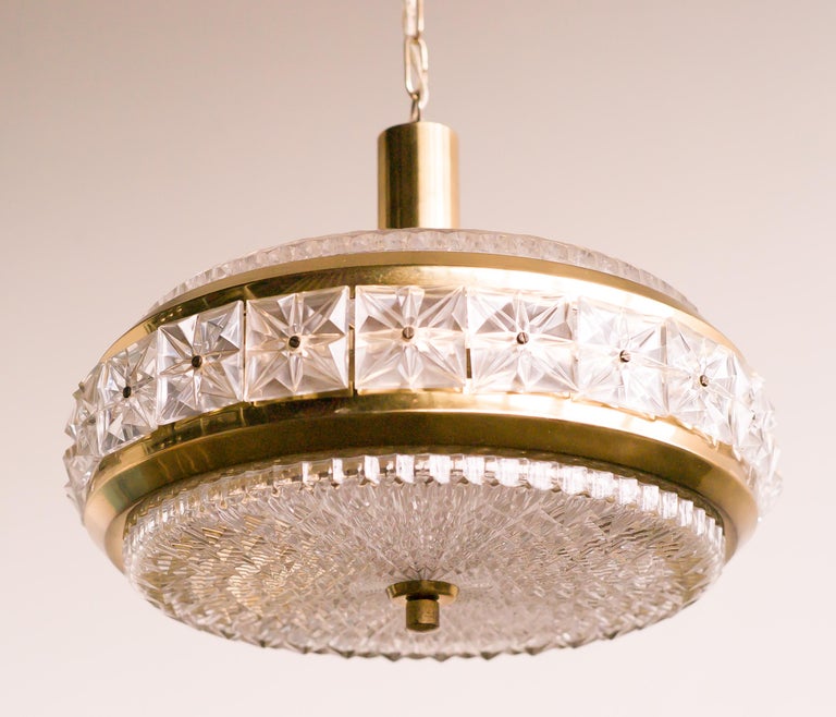 A Mid-Century Modern crystal and brass pendant consisting of multiple pieces of pressed glass around a brass frame designed by Carl Fagerlund for Orrefors, Sweden.