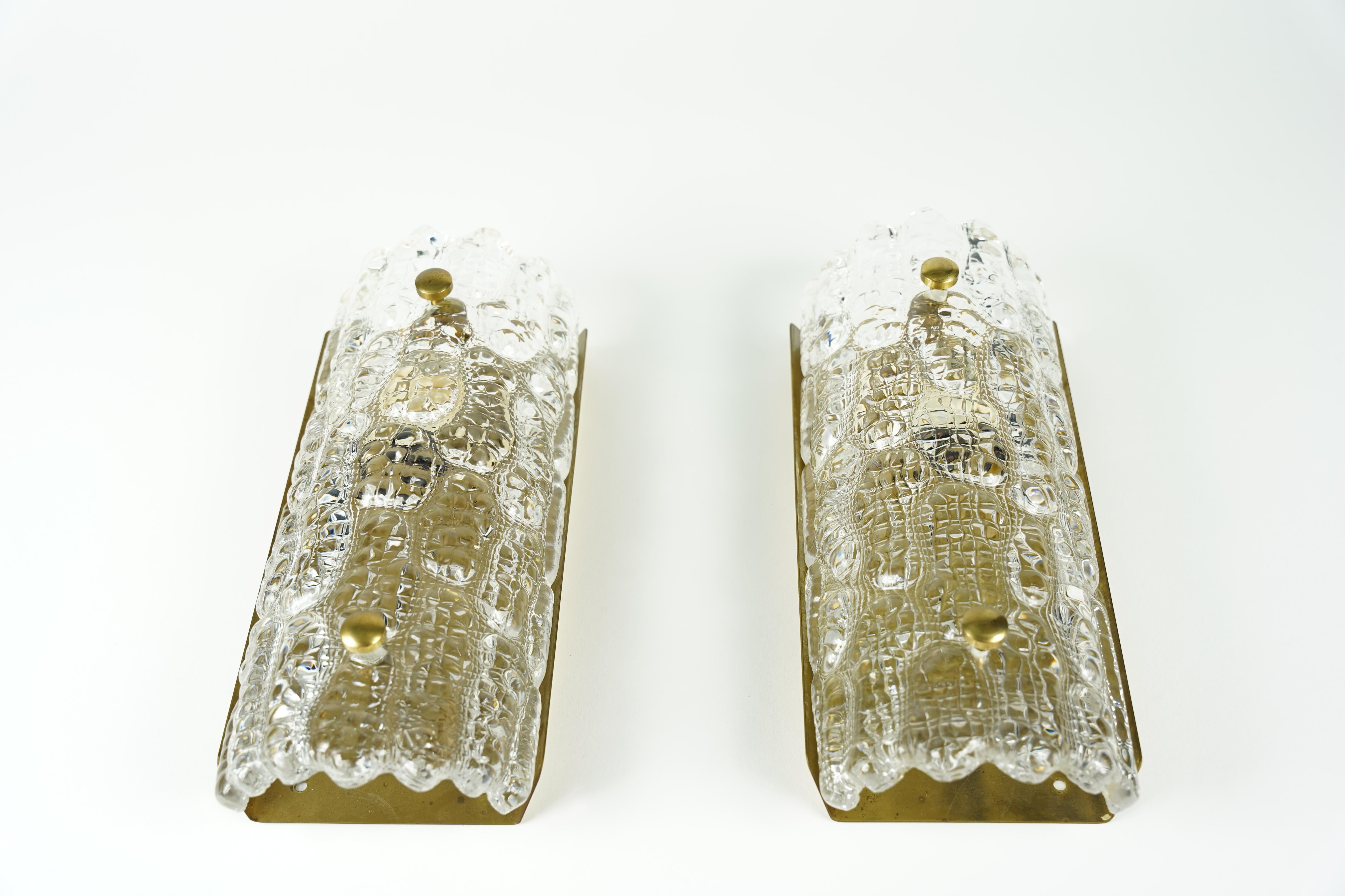 Pair of Orrefors clear glass sconces, crocodile pattern, glass shades are resting on a brass frame with brass fasteners.

Rewired for the US.

Holds one candelabra bulb each.