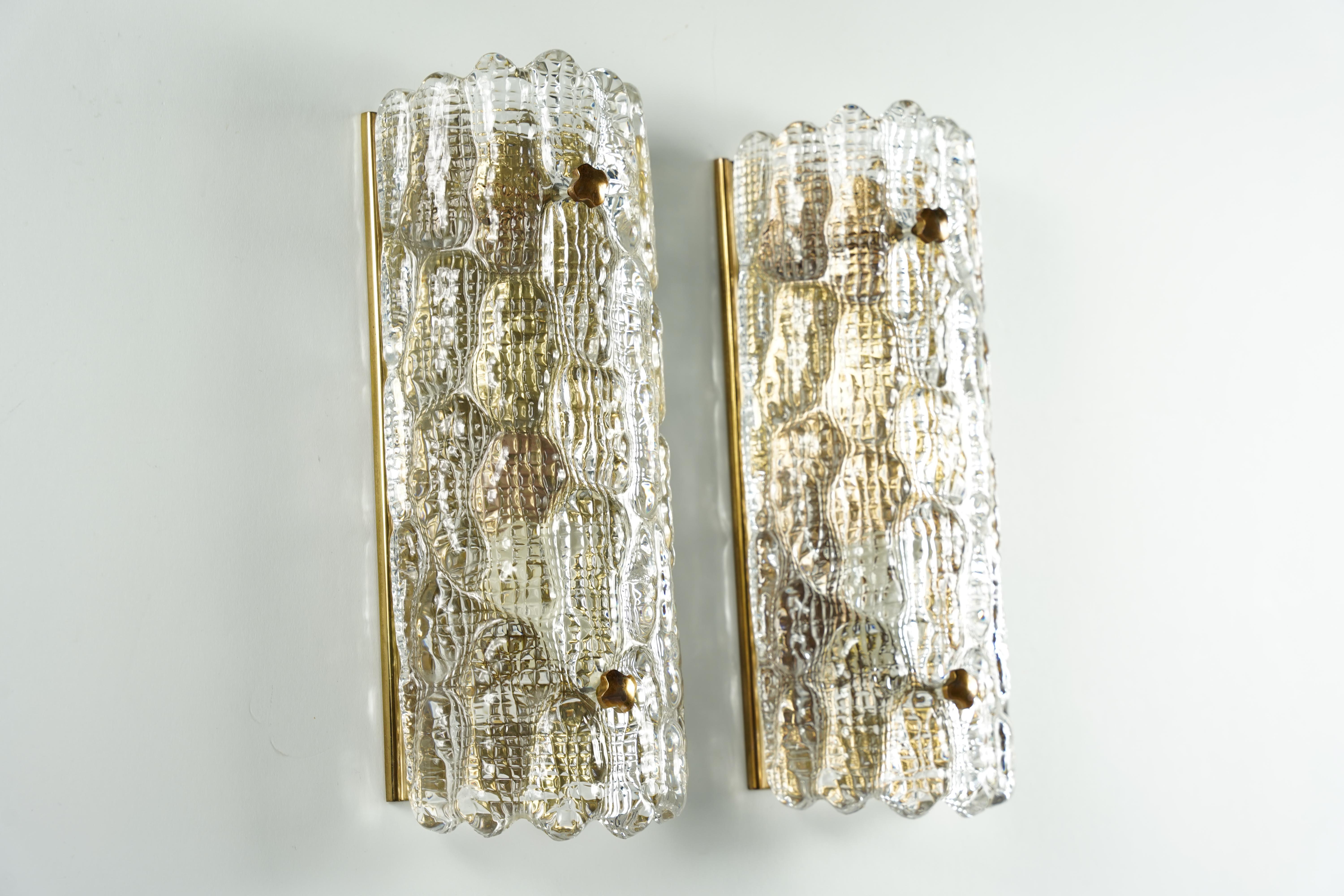 Pair of Orrefors clear glass sconces, crocodile pattern, glass shades are resting on a brass frame with brass fasteners.

Rewired for the US.

Holds one candelabra bulb each.