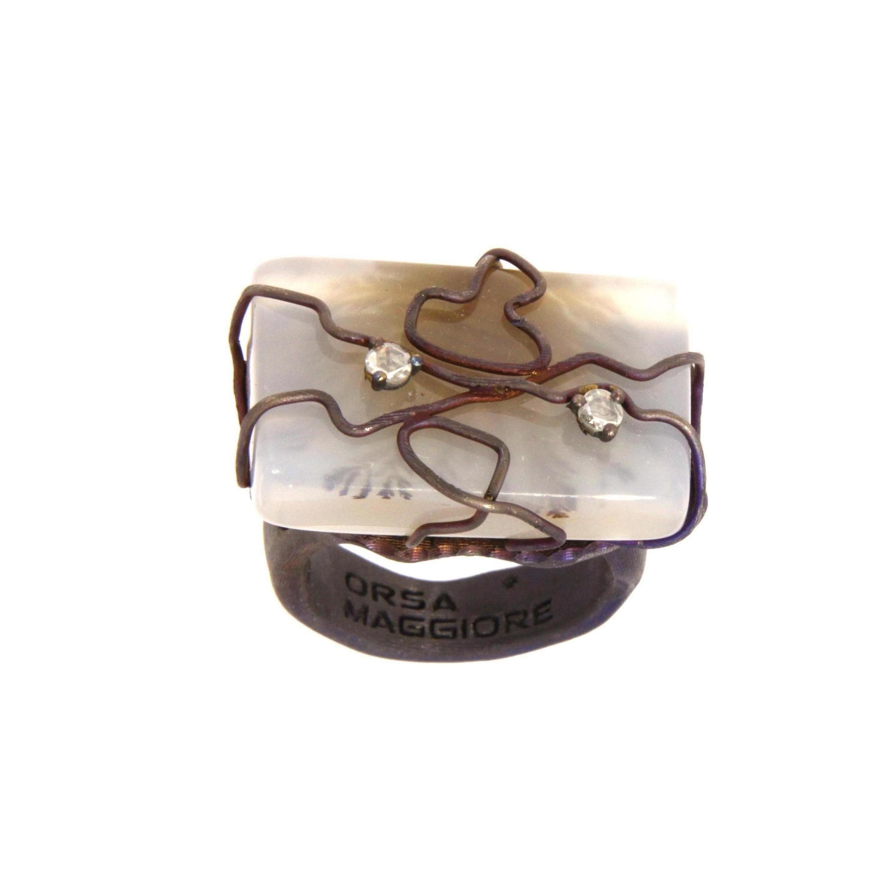 The ring is cast in titanium, with a blue-tinted silk-effect satin finish. 
It sets a rectangular moss agate with intertwined titanium wires and two rose-cut diamonds in claw settings.
The ring can be easily adjusted in size to the customer exigence