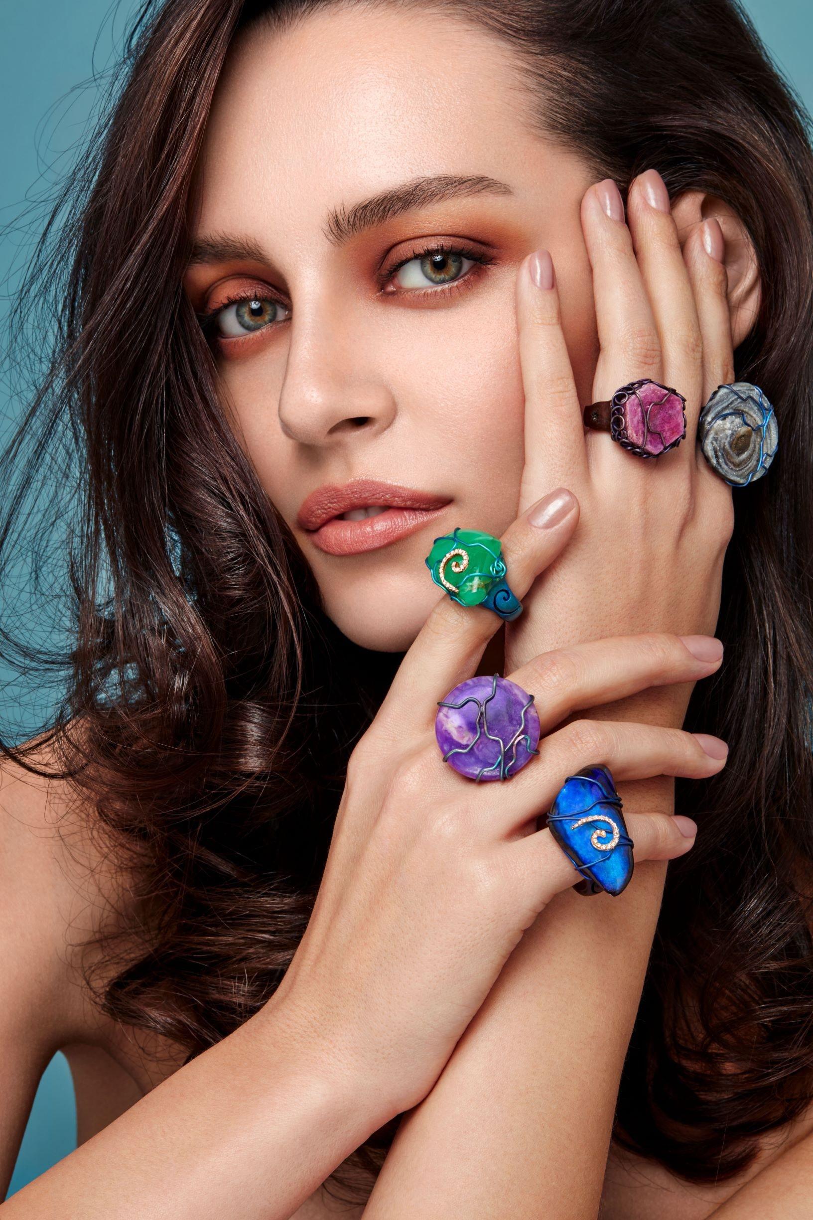 The ring is cast in titanium, with a blue tinted silk-effect satin finish. 
It sets a round purple sugillite with titanium wires.
Brilliant cut diamonds are embedded to give more sparkle to the stone.
The ring can be easily adjusted in size to the
