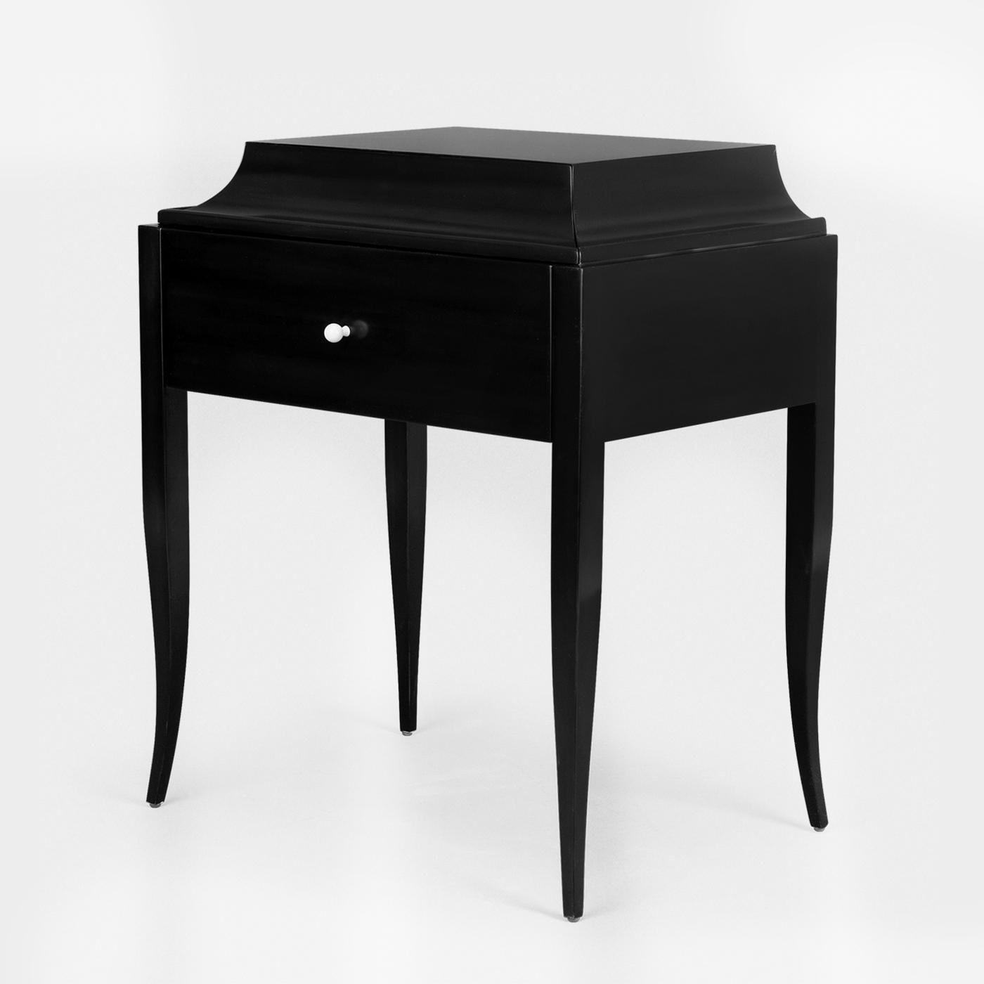 Nightstand or side table Ortens with handcrafted
solid mahogany wood structure in black lacquered
finish. With 1 drawer.
Also available in ivory lacquered, white lacquered,
or natural tobacco finish.