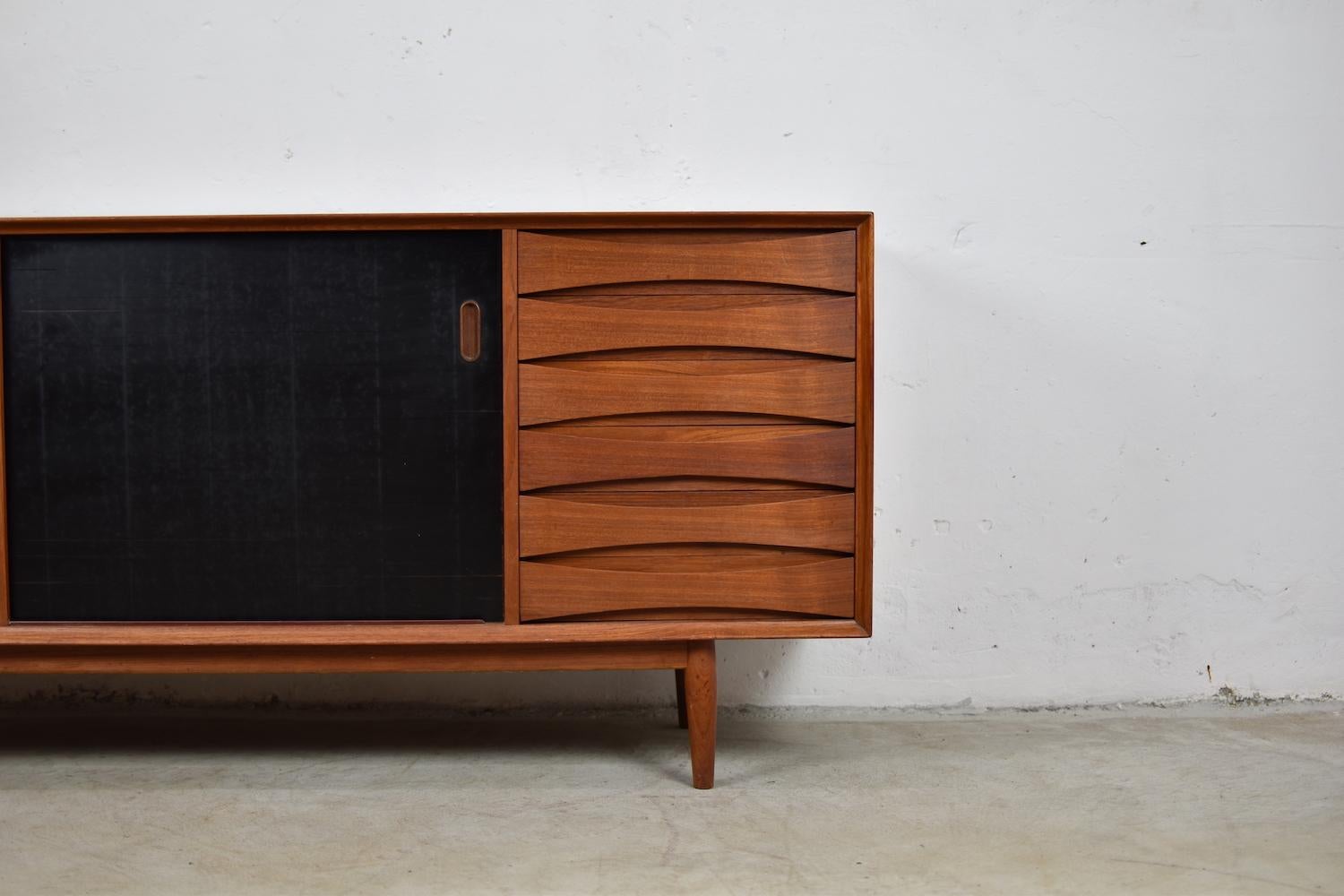 Lovely OS29 sideboard by Arne Vodder for Sibast Mobler, Denmark, 1958. This rare cabinet is made out of teak and has two sliding doors that are reversible to teak and black lacquer. On the right a series of marvelous curved drawers. Typical raised